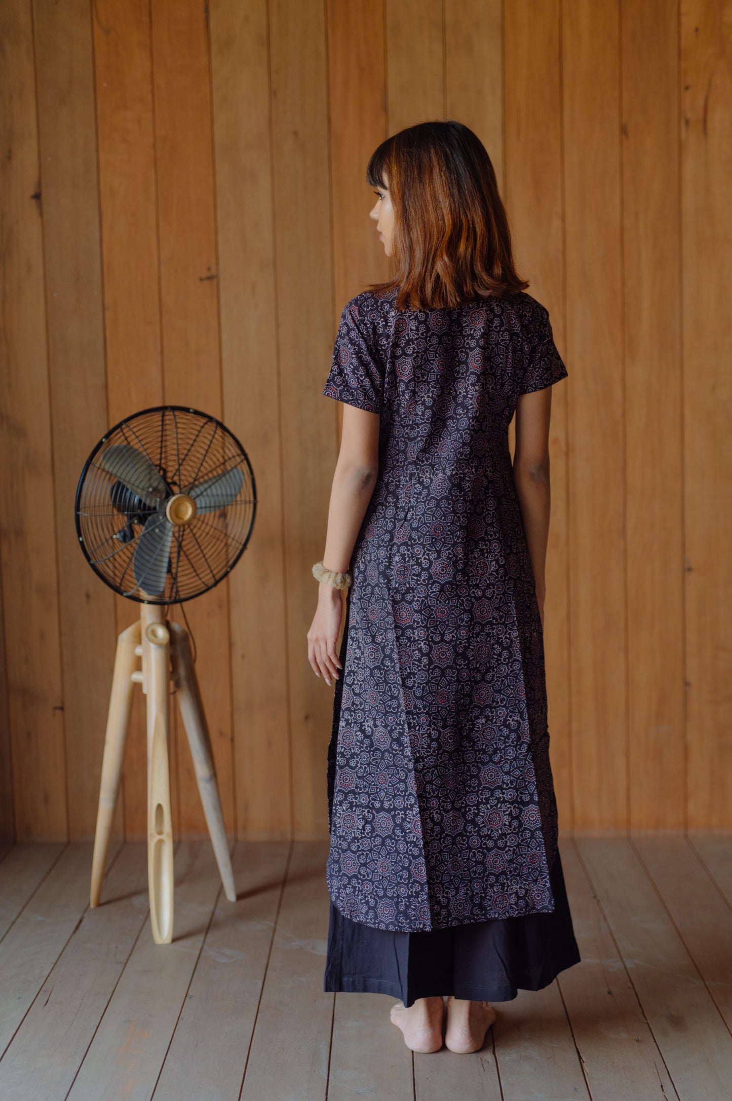Black natural dyed Ajrakh hand block printed cotton kurta with curved V neck, short sleeves and U-hemline paired with plain black cotton palazzo pants featuring elasticated waist. Handmade, breathable, slow made Indian wear crafted in Gujarat.