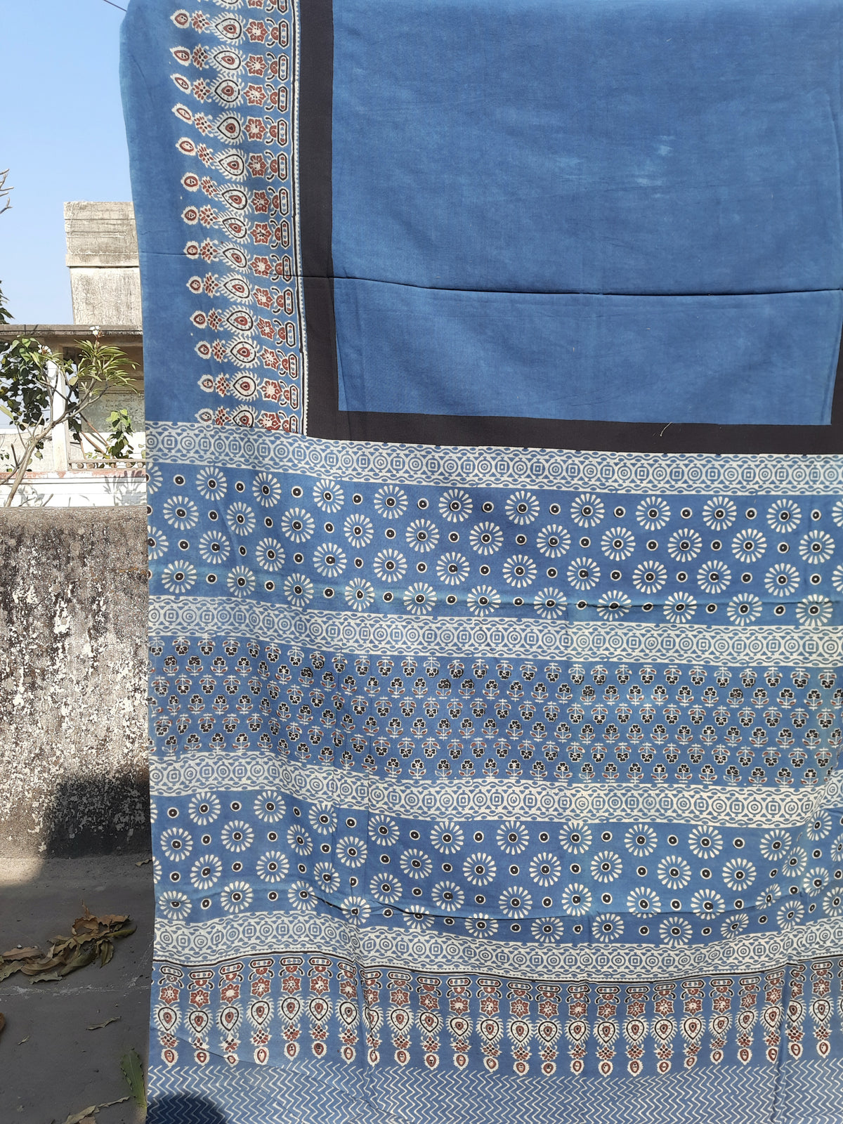 Solid indigo dyed Ajrakh hand block printed cotton saree featuring a calm indigo body with intricately printed Ajrakh borders and pallu. Natural dyed, breathable and slow made saree handcrafted by artisans in Gujarat.