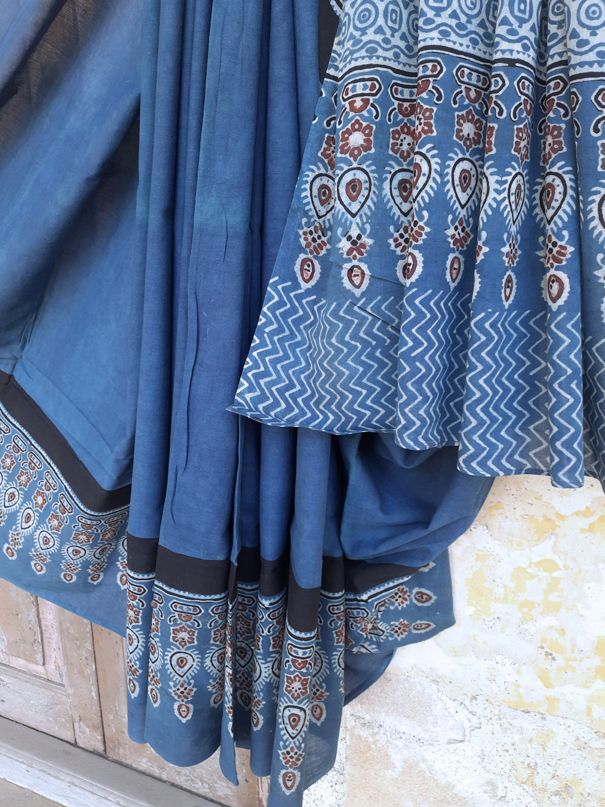 Solid indigo dyed Ajrakh hand block printed cotton saree featuring a calm indigo body with intricately printed Ajrakh borders and pallu. Natural dyed, breathable and slow made saree handcrafted by artisans in Gujarat.