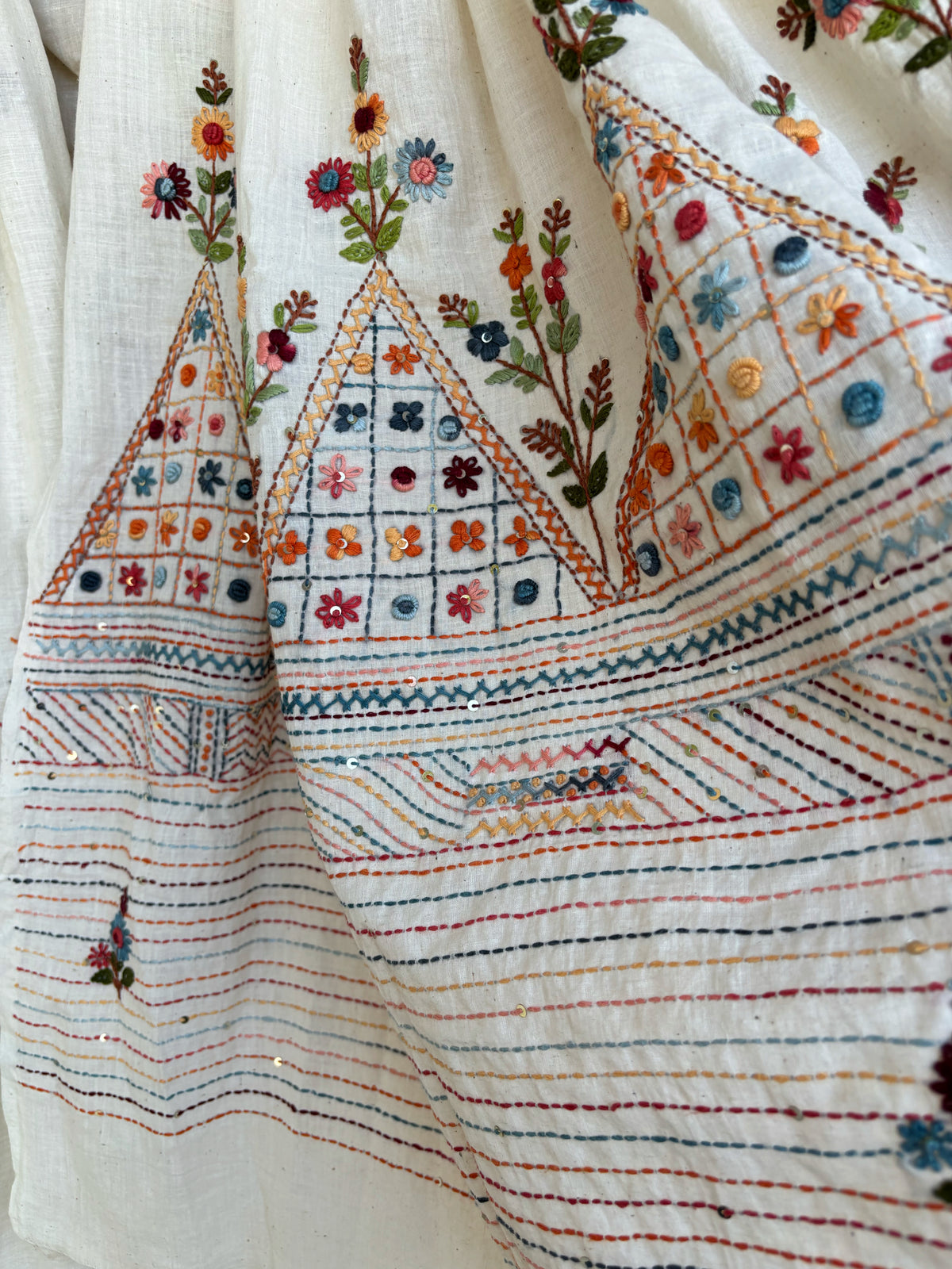 Handspun and handwoven cotton saree in warm ivory shade, featuring delicate hand embroidered floral and linear motifs with subtle sequin detailing. Slow made artisanal saree named Kusum, paired with a hand embroidered blouse piece.