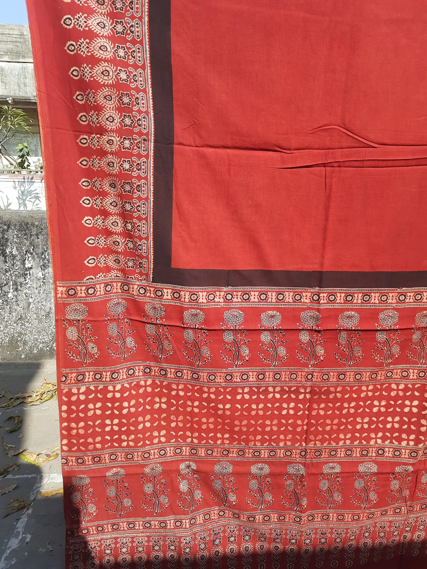 Madder red cotton Ajrakh hand block print saree featuring a solid dyed body, intricately printed Ajrakh borders, and a richly patterned pallu, naturally dyed using madder with a running blouse piece, handcrafted in India.