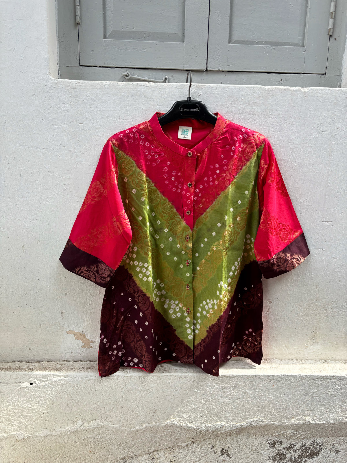 Handcrafted Bandhani festive cotton shirt in Rani Pink, Olive Green and Deep Wine Maroon with antique gold woven floral motifs, round band neckline, short button placket, relaxed fit and three-quarter sleeves.