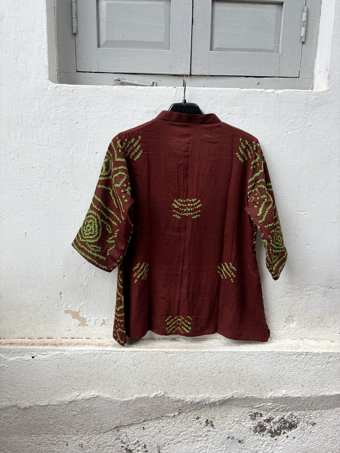 Deep mahogany brown cotton Jhankaar Bandhani shirt with vibrant parrot green motifs, handcrafted elephant details on the sleeve hems, soft mandarin collar and relaxed fit.