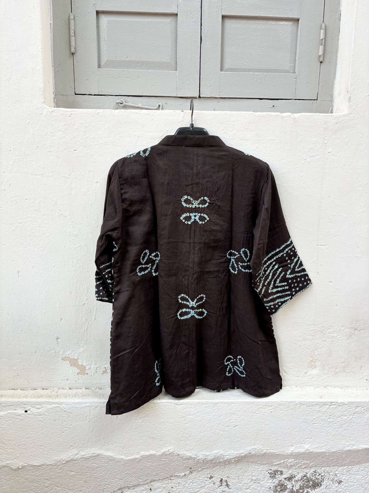 Handmade Jhankar Rai Dani Bandhani cotton shirt in charcoal black with dusty turquoise floral motifs, soft mandarin collar, Bandhani cuffs, relaxed fit, and short side slits.
