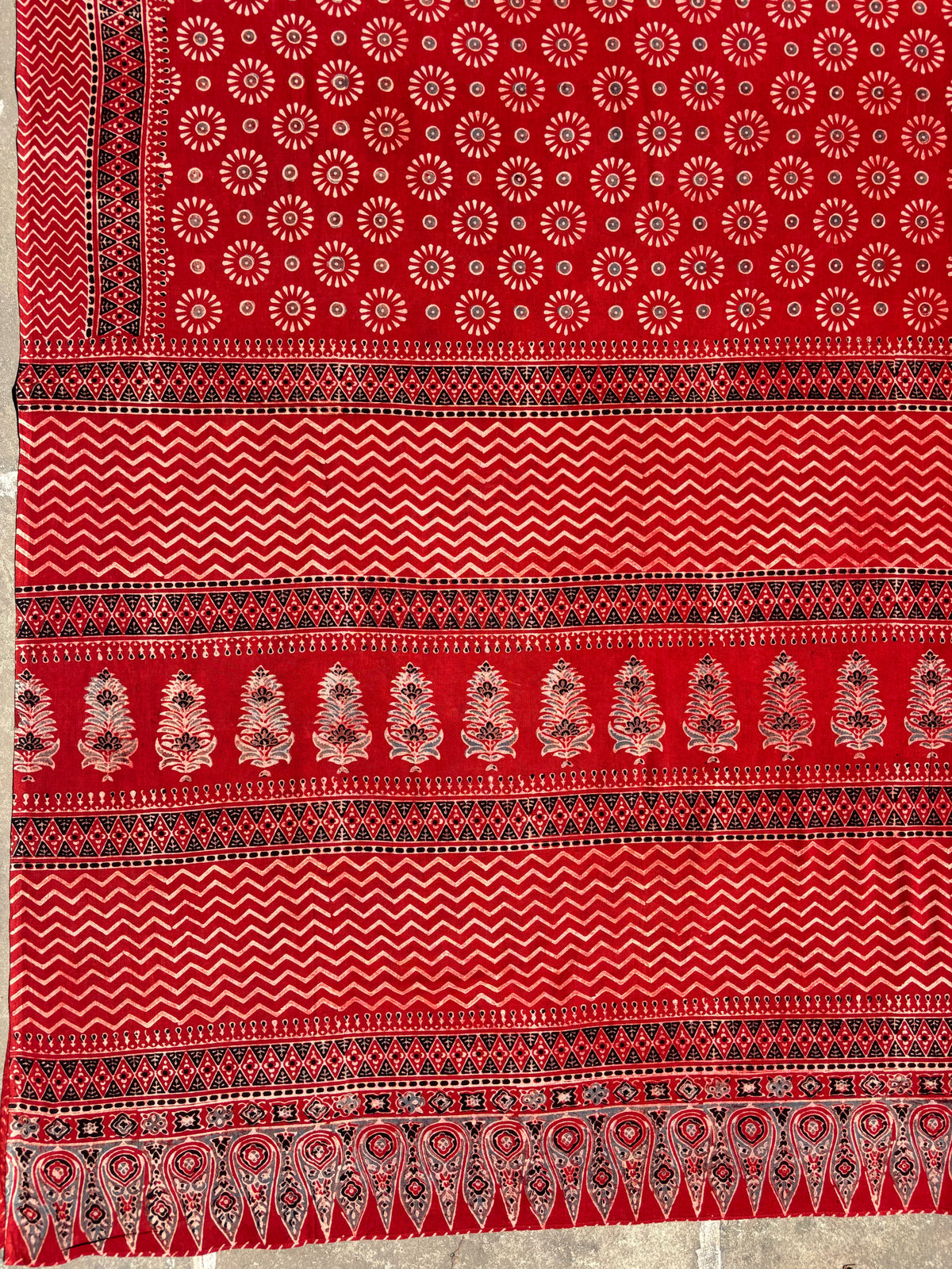 Madder dyed Ajrakh hand block printed cotton saree featuring circular motifs and geometric borders in deep red natural dye.