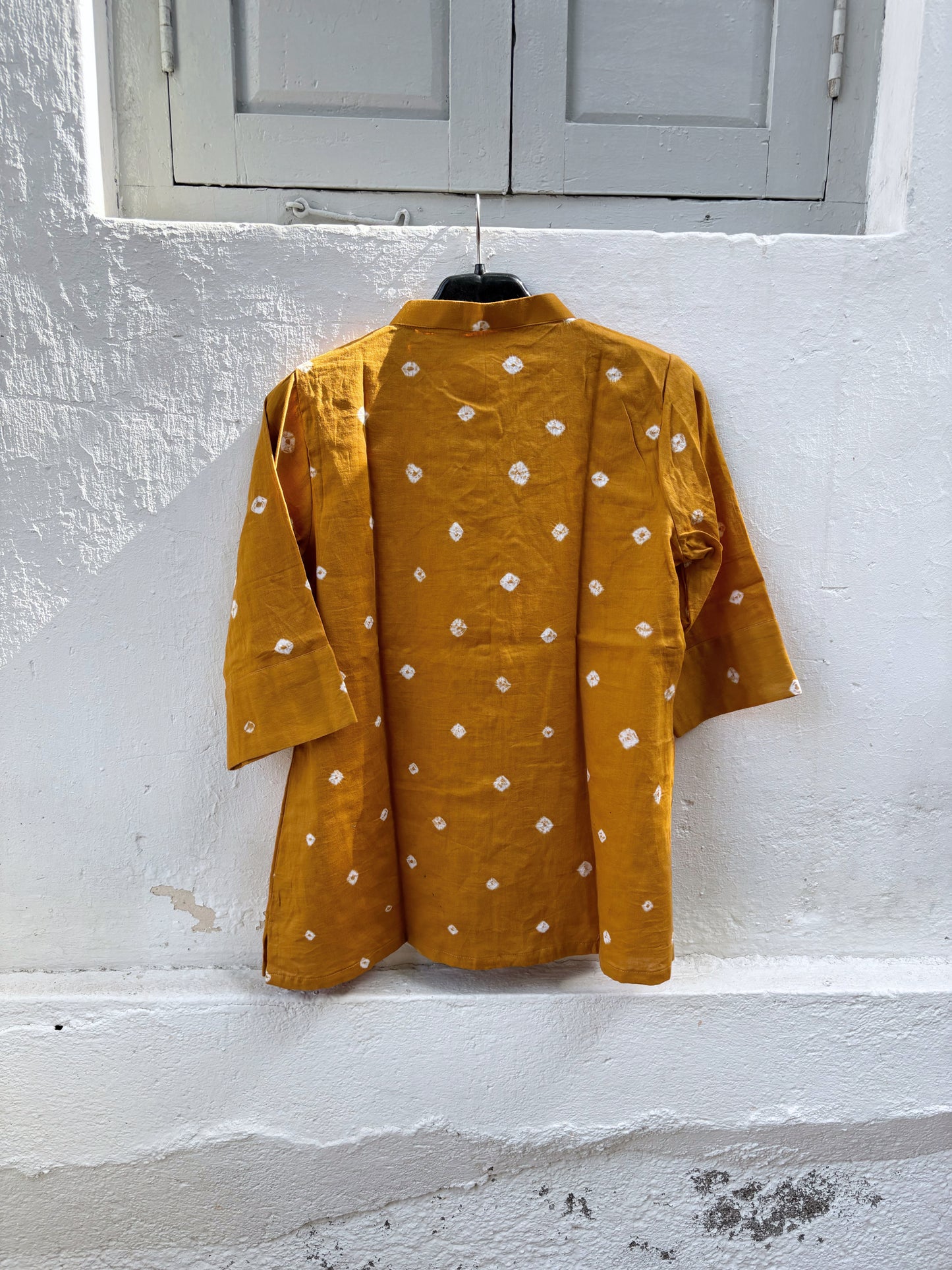 Marigold hand tie-dyed Bandhani cotton satin shirt in warm golden ochre with scattered white Bandhani motifs and a soft mandarin collar.