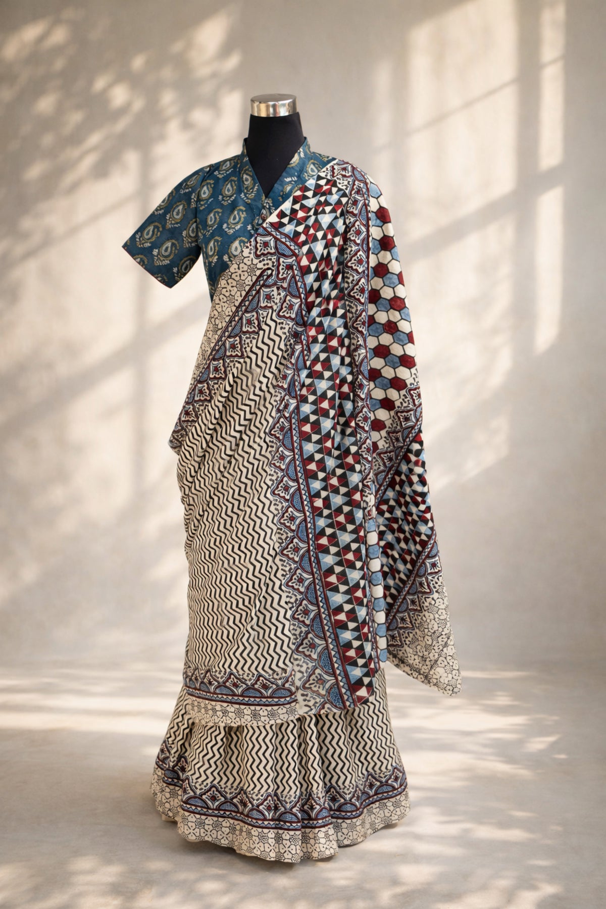 Myrobalan dyed pure cotton saree featuring traditional Ajrakh hand block prints with geometric motifs in indigo, madder red, and black tones, styled with a contrasting blouse.