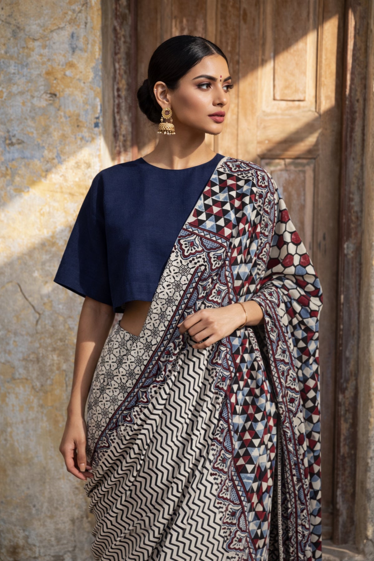 Myrobalan dyed pure cotton saree featuring traditional Ajrakh hand block prints with geometric motifs in indigo, madder red, and black tones, styled with a contrasting blouse.