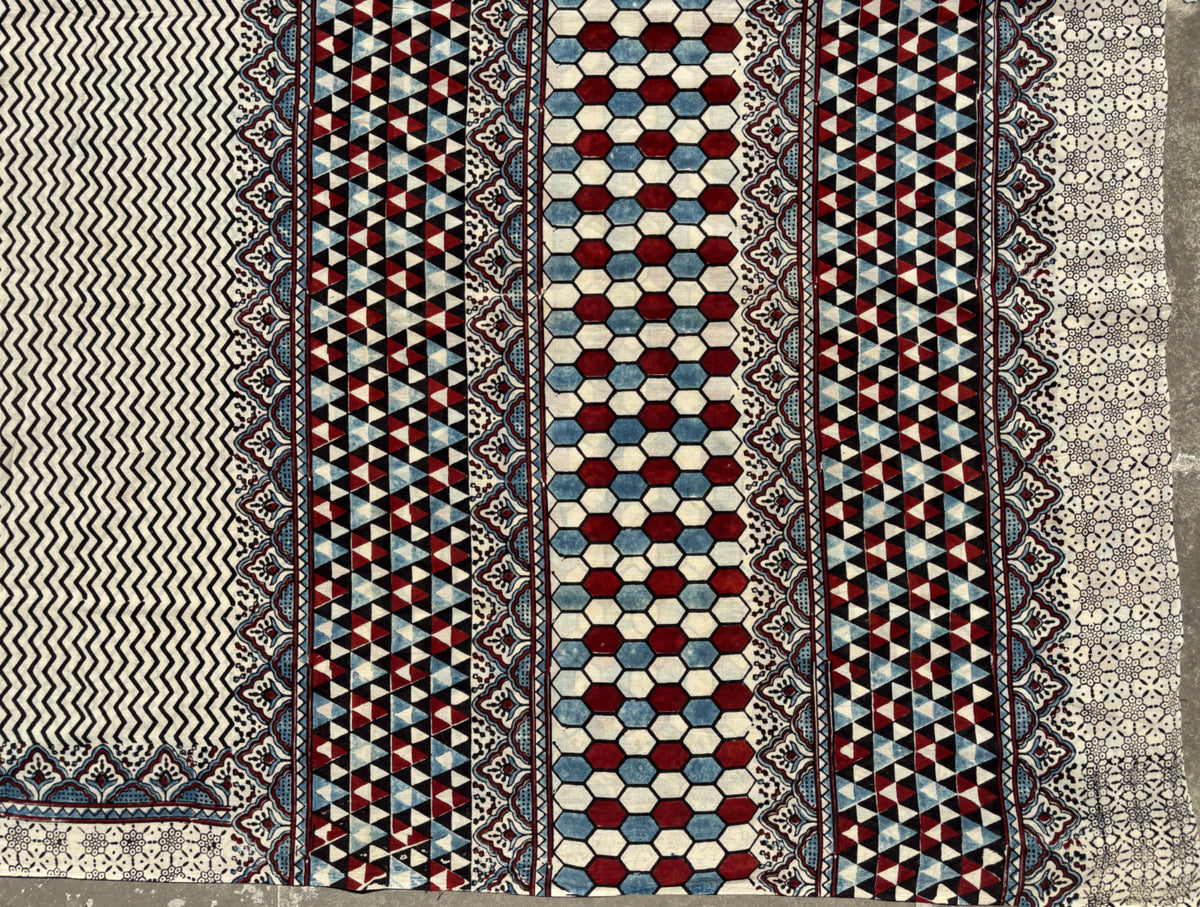 Myrobalan dyed pure cotton saree featuring traditional Ajrakh hand block prints with geometric motifs in indigo, madder red, and black tones, styled with a contrasting blouse.