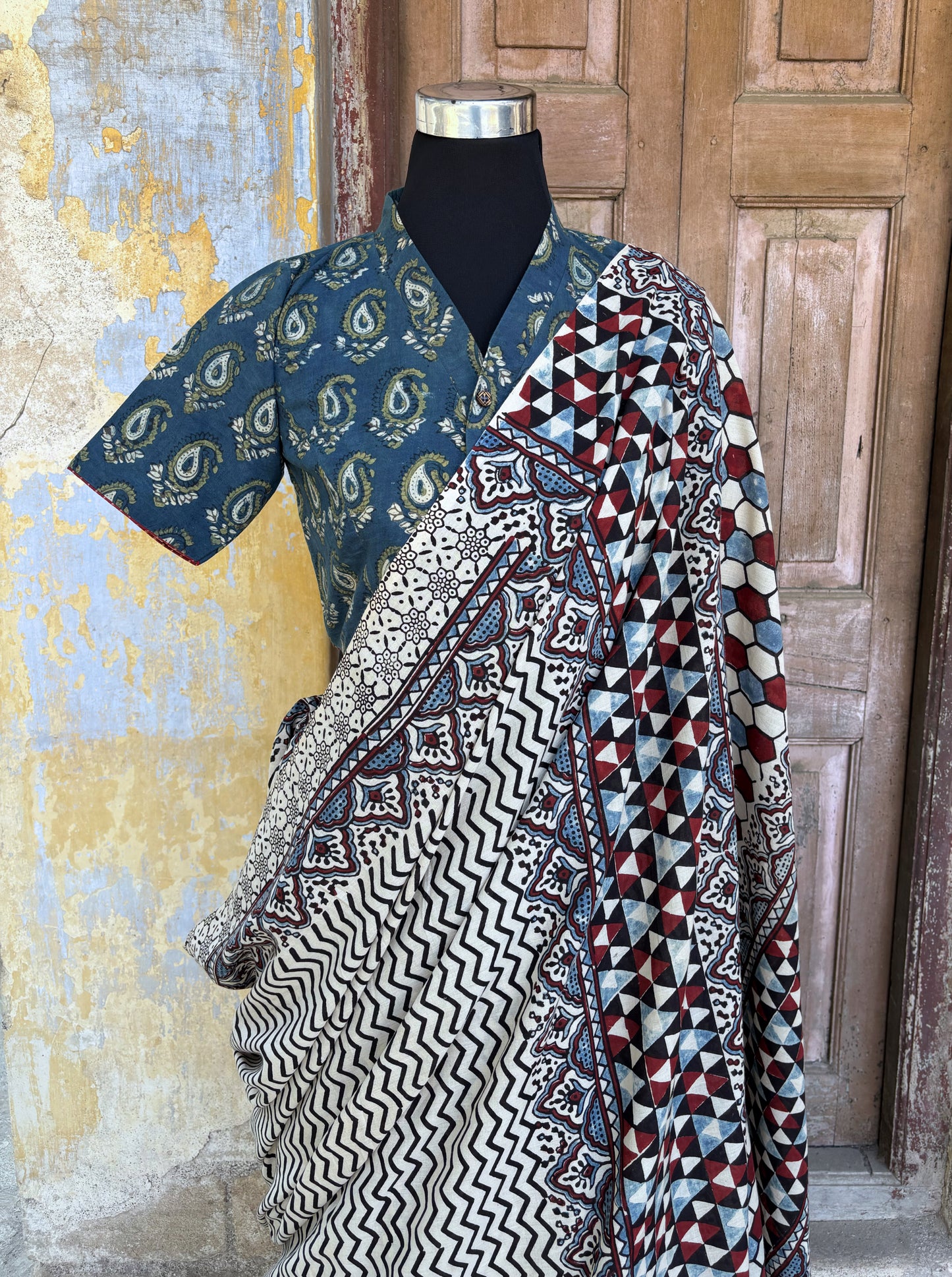 Myrobalan dyed pure cotton saree featuring traditional Ajrakh hand block prints with geometric motifs in indigo, madder red, and black tones, styled with a contrasting blouse.