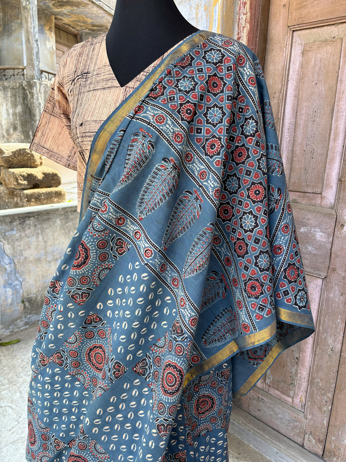 Indigo Ajrakh hand block printed cotton saree featuring traditional circular and geometric motifs with a thin border, paired with a madder dyed Ajrakh blouse piece.