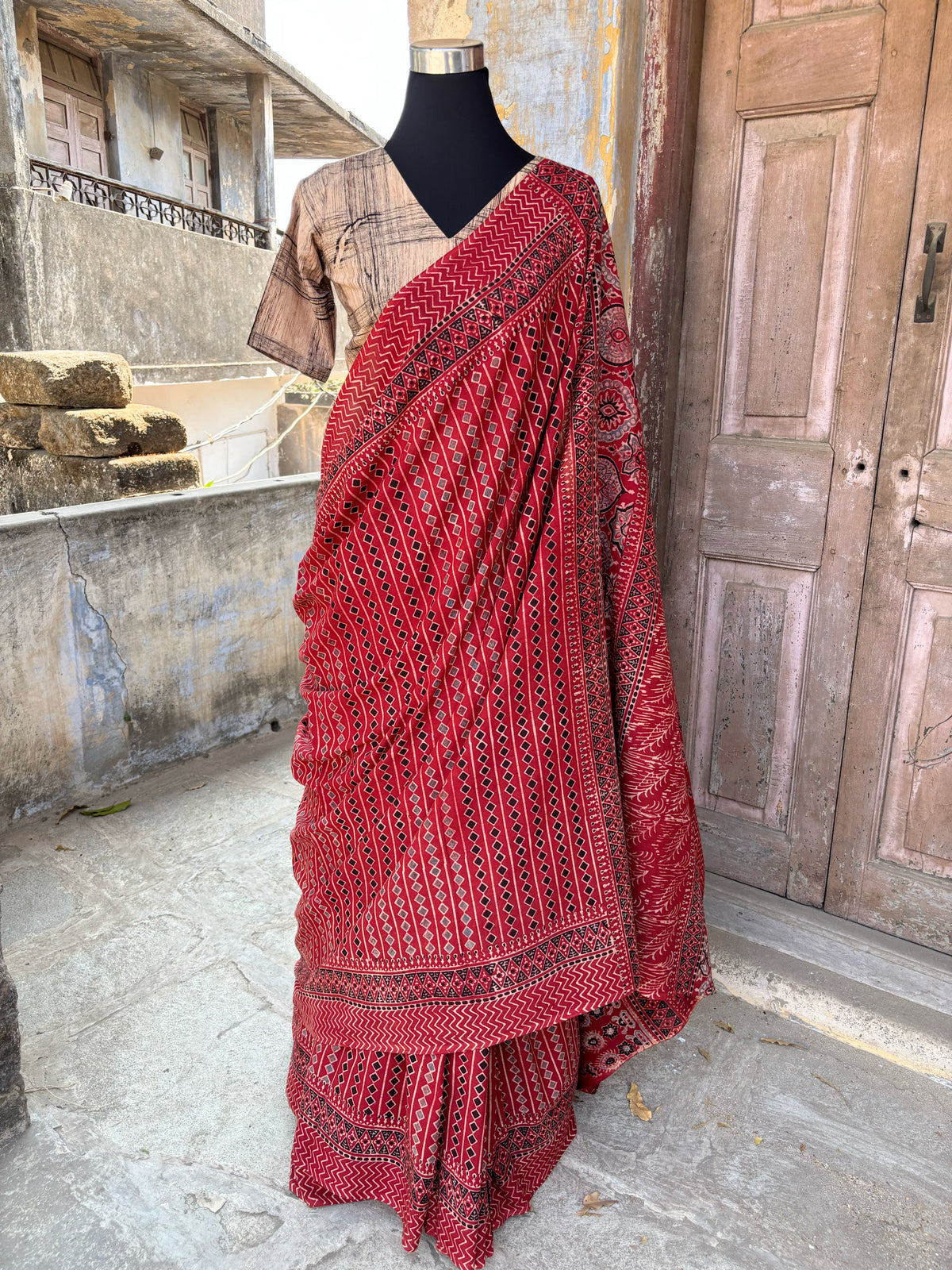 Madder dyed cotton Ajrakh hand block printed saree featuring traditional geometric motifs in red, black, and beige with detailed borders and pallu.