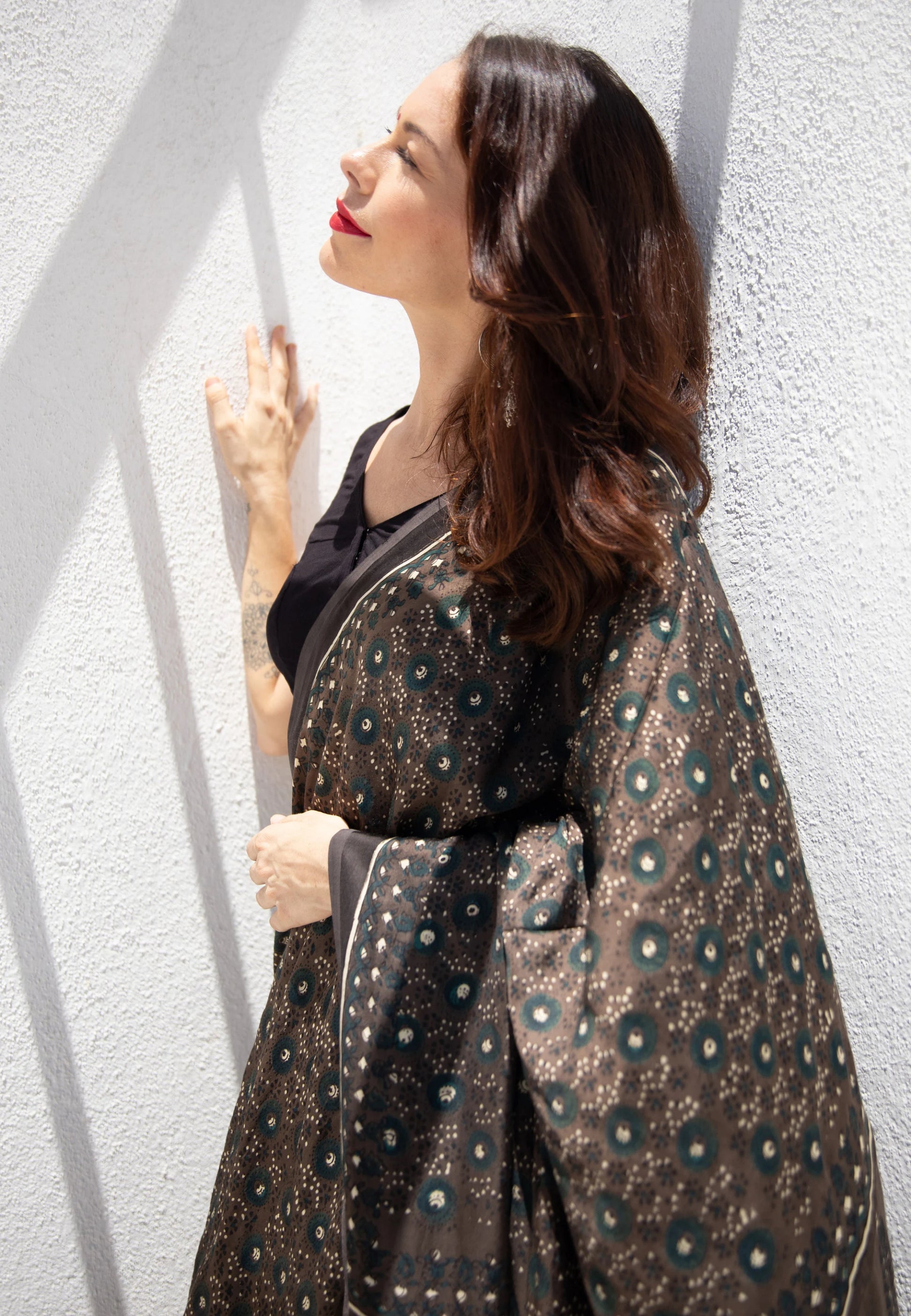 Grey Ajrakh hand block printed modal silk saree, naturally dyed and handcrafted by artisans in Gujarat, India. Features soft luxurious drape, intricate prints, tasselled pallu, and a running blouse inside.