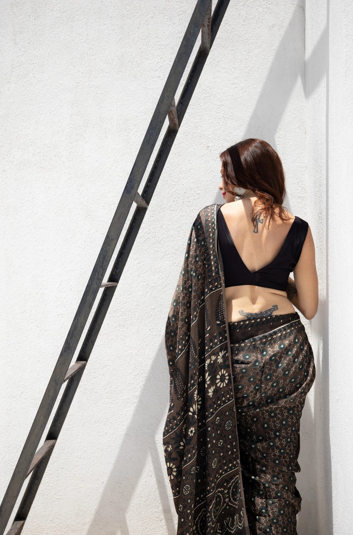 Grey Ajrakh hand block printed modal silk saree, naturally dyed and handcrafted by artisans in Gujarat, India. Features soft luxurious drape, intricate prints, tasselled pallu, and a running blouse inside.
