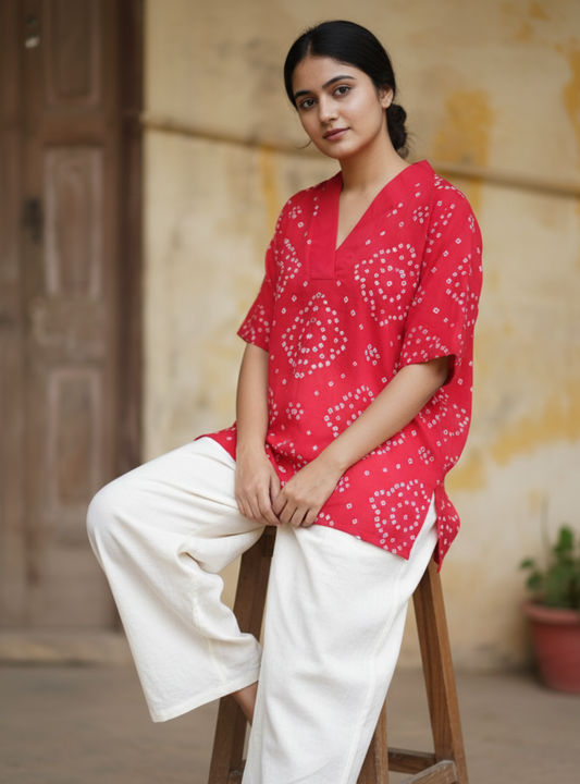 A deep pink, handcrafted cotton satin bandhani oversized top for women. This comfortable, loose-fit designer top features a traditional hand tie-dyed pattern, short side slits, and a V-neckline, perfect for casual or everyday ethnic wear. Ideal for a modern, relaxed style.