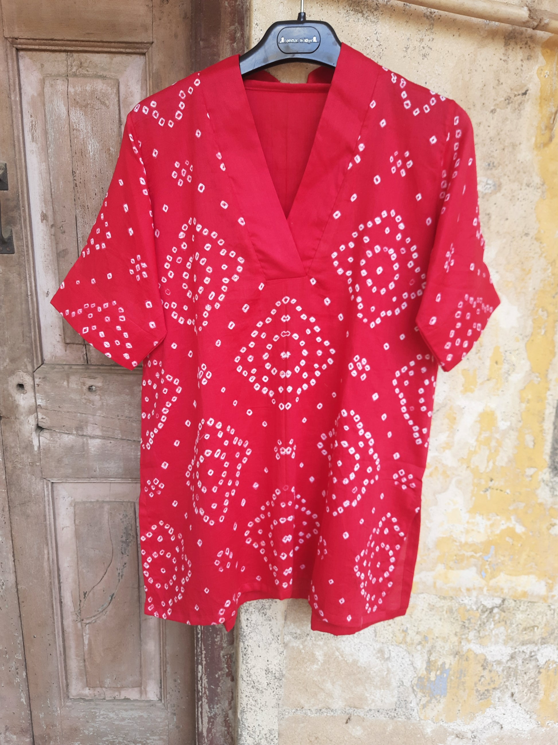 A deep pink, handcrafted cotton satin bandhani oversized top for women. This comfortable, loose-fit designer top features a traditional hand tie-dyed pattern, short side slits, and a V-neckline, perfect for casual or everyday ethnic wear. Ideal for a modern, relaxed style.