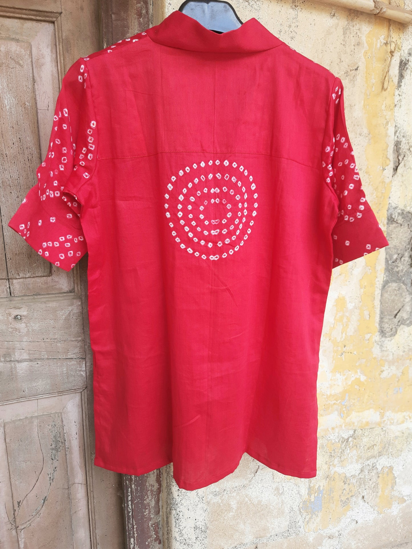 A deep pink, handcrafted cotton satin bandhani oversized top for women. This comfortable, loose-fit designer top features a traditional hand tie-dyed pattern, short side slits, and a V-neckline, perfect for casual or everyday ethnic wear. Ideal for a modern, relaxed style.