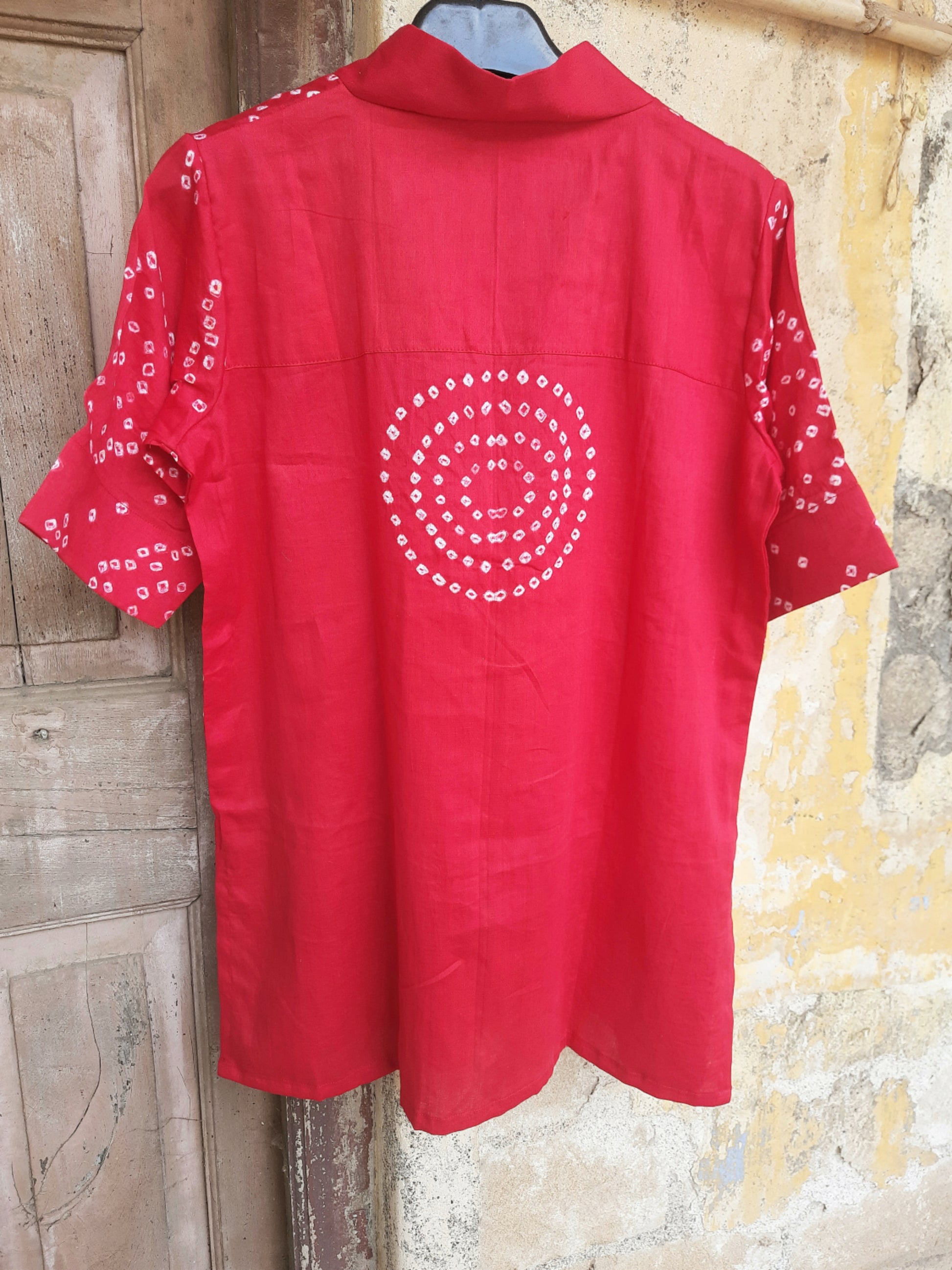 A deep pink, handcrafted cotton satin bandhani oversized top for women. This comfortable, loose-fit designer top features a traditional hand tie-dyed pattern, short side slits, and a V-neckline, perfect for casual or everyday ethnic wear. Ideal for a modern, relaxed style.