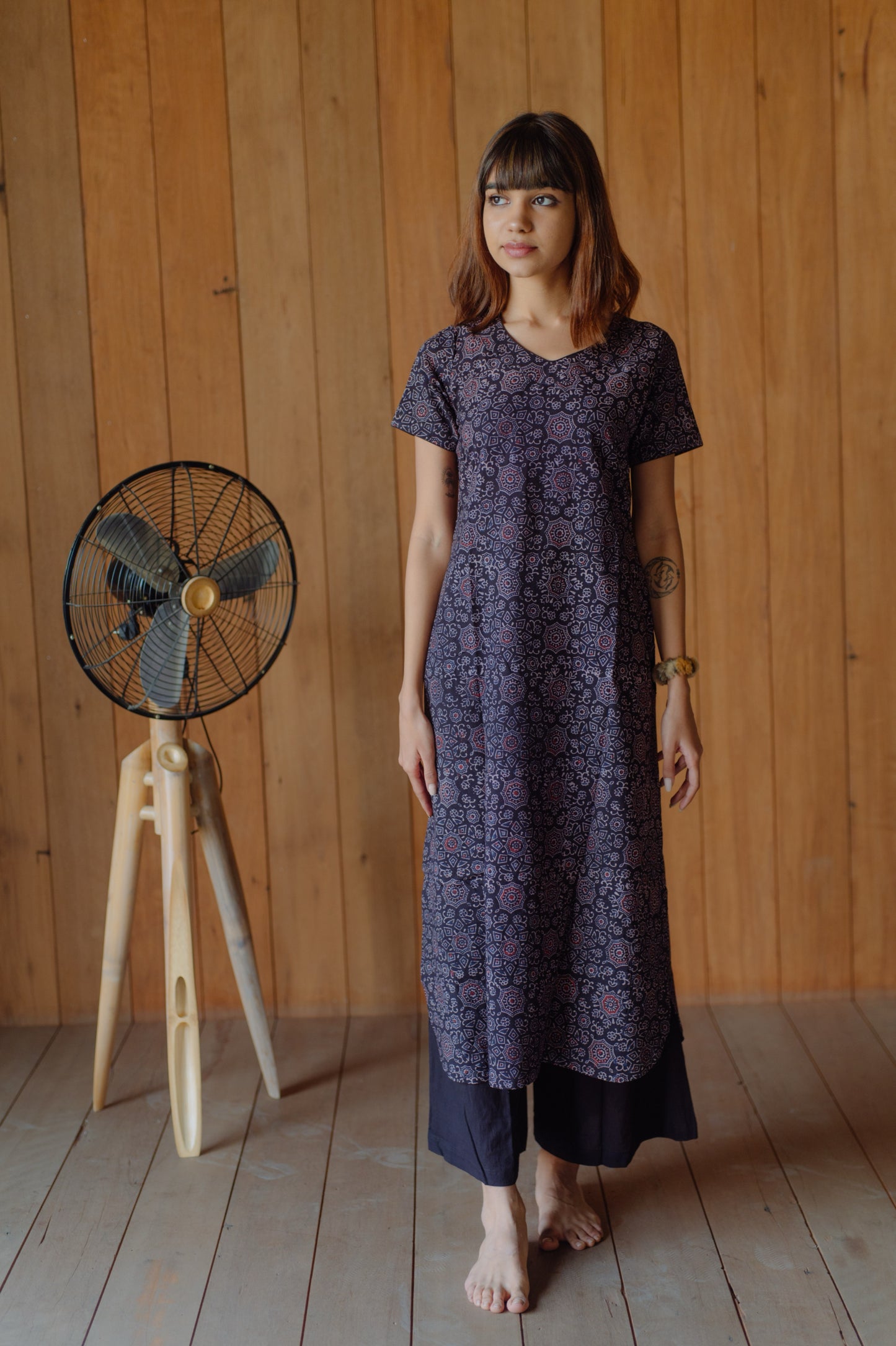 Black natural dyed Ajrakh hand block printed cotton kurta with curved V neck, short sleeves and U-hemline paired with plain black cotton palazzo pants featuring elasticated waist. Handmade, breathable, slow made Indian wear crafted in Gujarat.