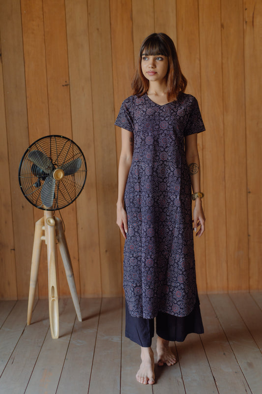 Black natural dyed Ajrakh hand block printed cotton kurta with curved V neck, short sleeves and U-hemline paired with plain black cotton palazzo pants featuring elasticated waist. Handmade, breathable, slow made Indian wear crafted in Gujarat.