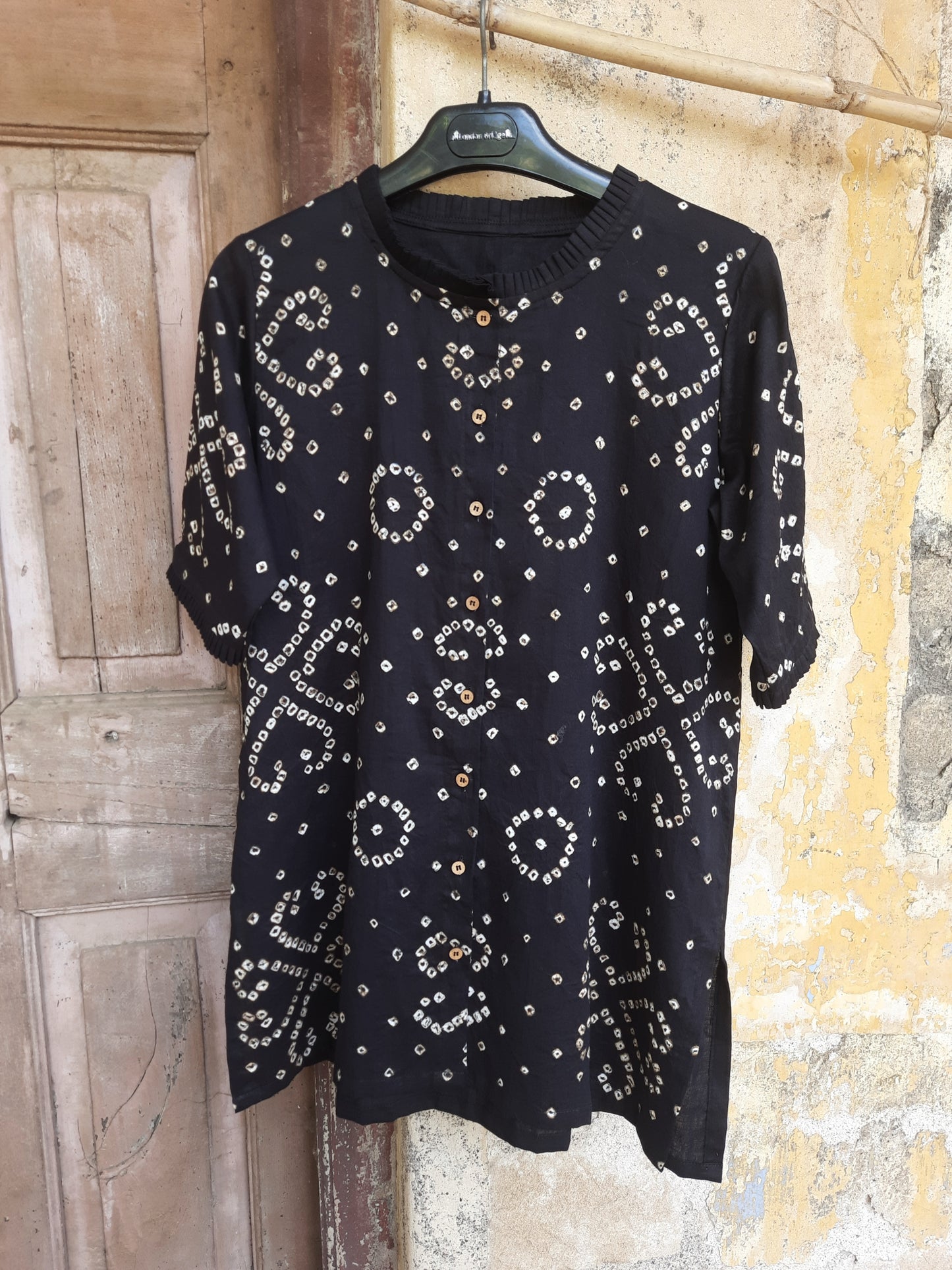 Handcrafted oversized black Bandhani shirt for women, made in cotton satin with pleated neck, 3/4th sleeves, short side slits, and traditional tie-dye detailing.