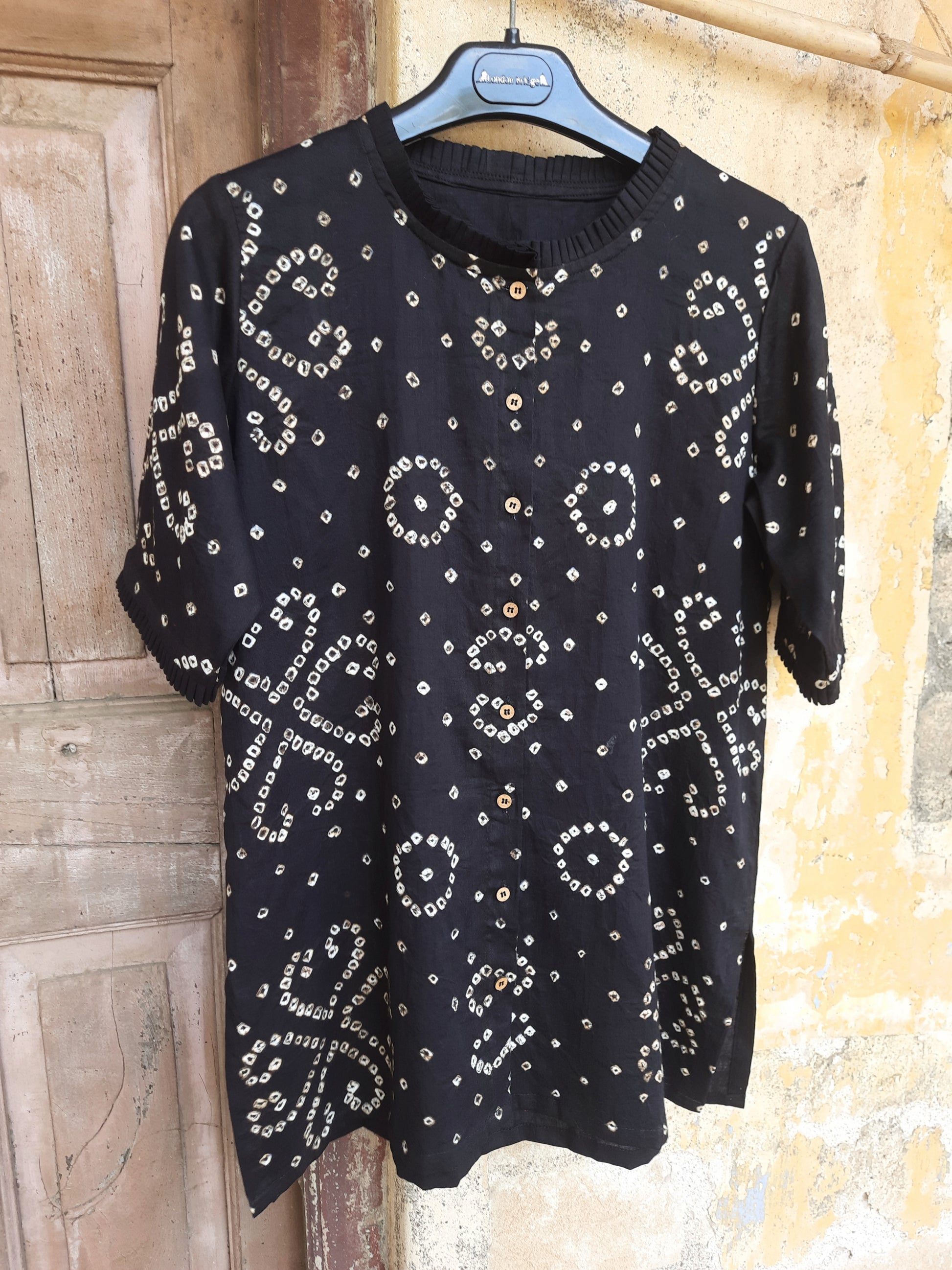Handcrafted oversized black Bandhani shirt for women, made in cotton satin with pleated neck, elbow sleeves, short side slits, and traditional tie-dye detailing.
