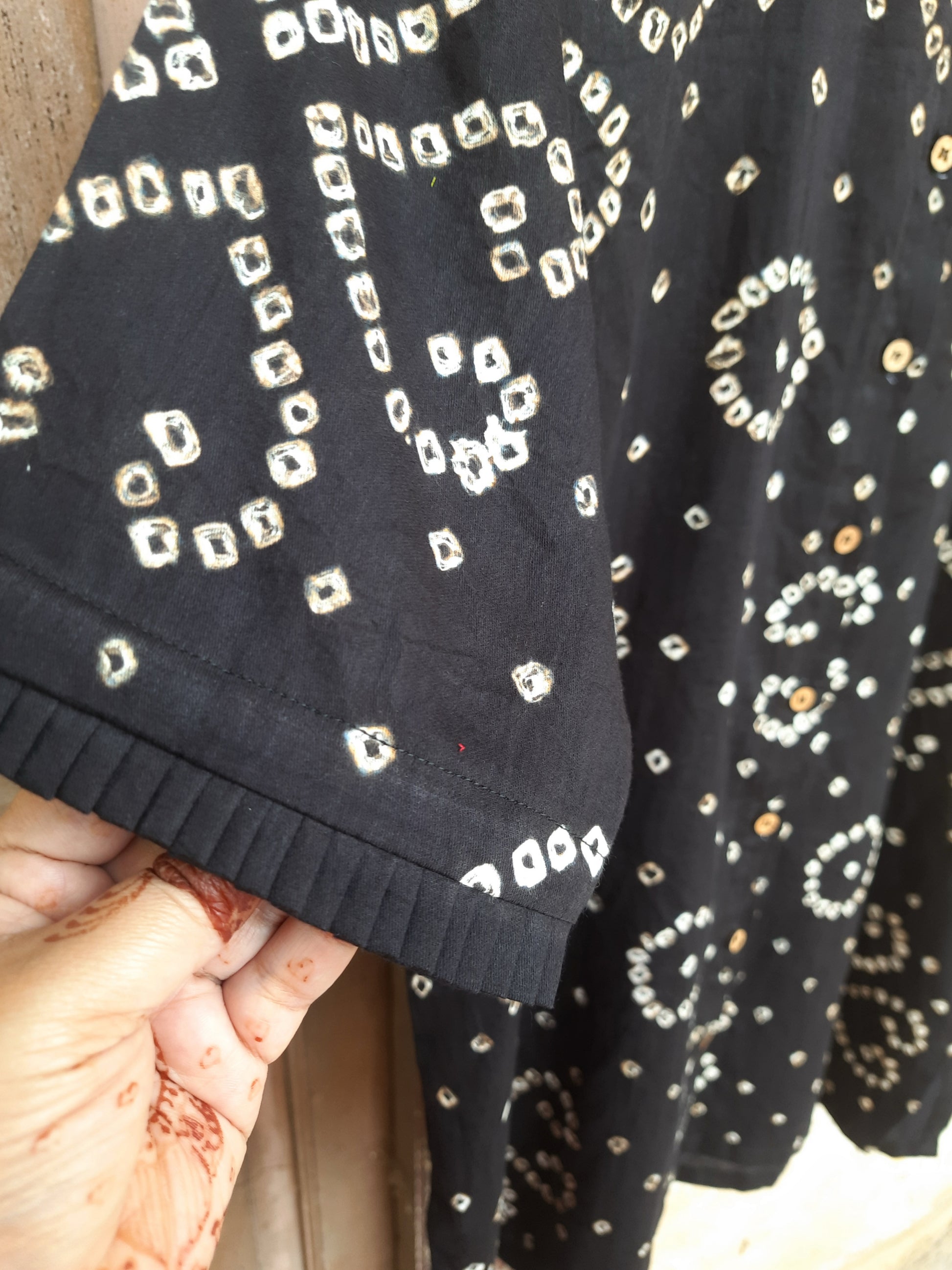 Handcrafted oversized black Bandhani shirt for women, made in cotton satin with pleated neck, elbow sleeves, short side slits, and traditional tie-dye detailing.