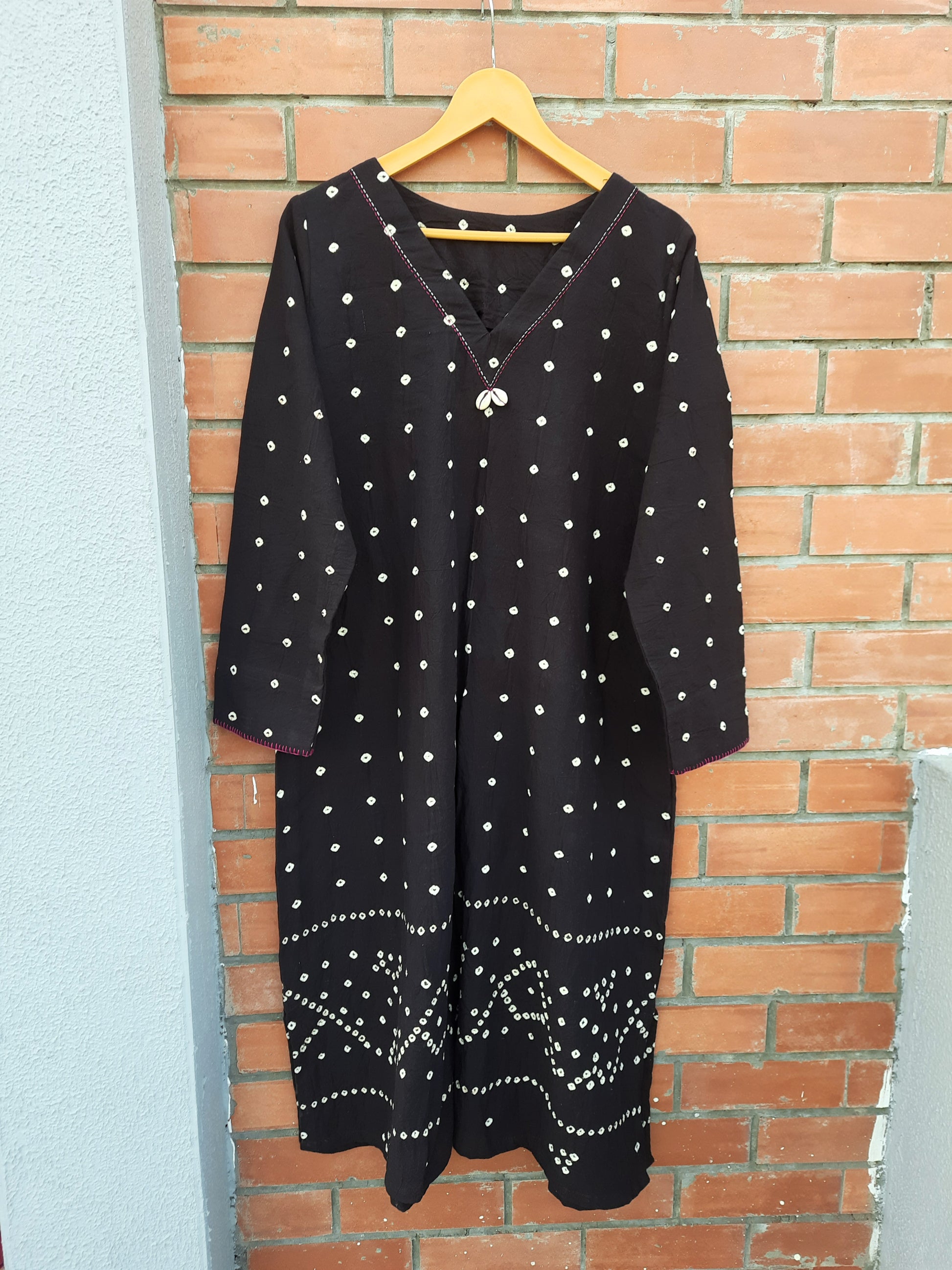 Handwoven organic cotton oversized Bandhani kurta for women with V-neck, cowrie detailing, full sleeves, and hand tie-dyed design handcrafted by artisans of Gujarat.