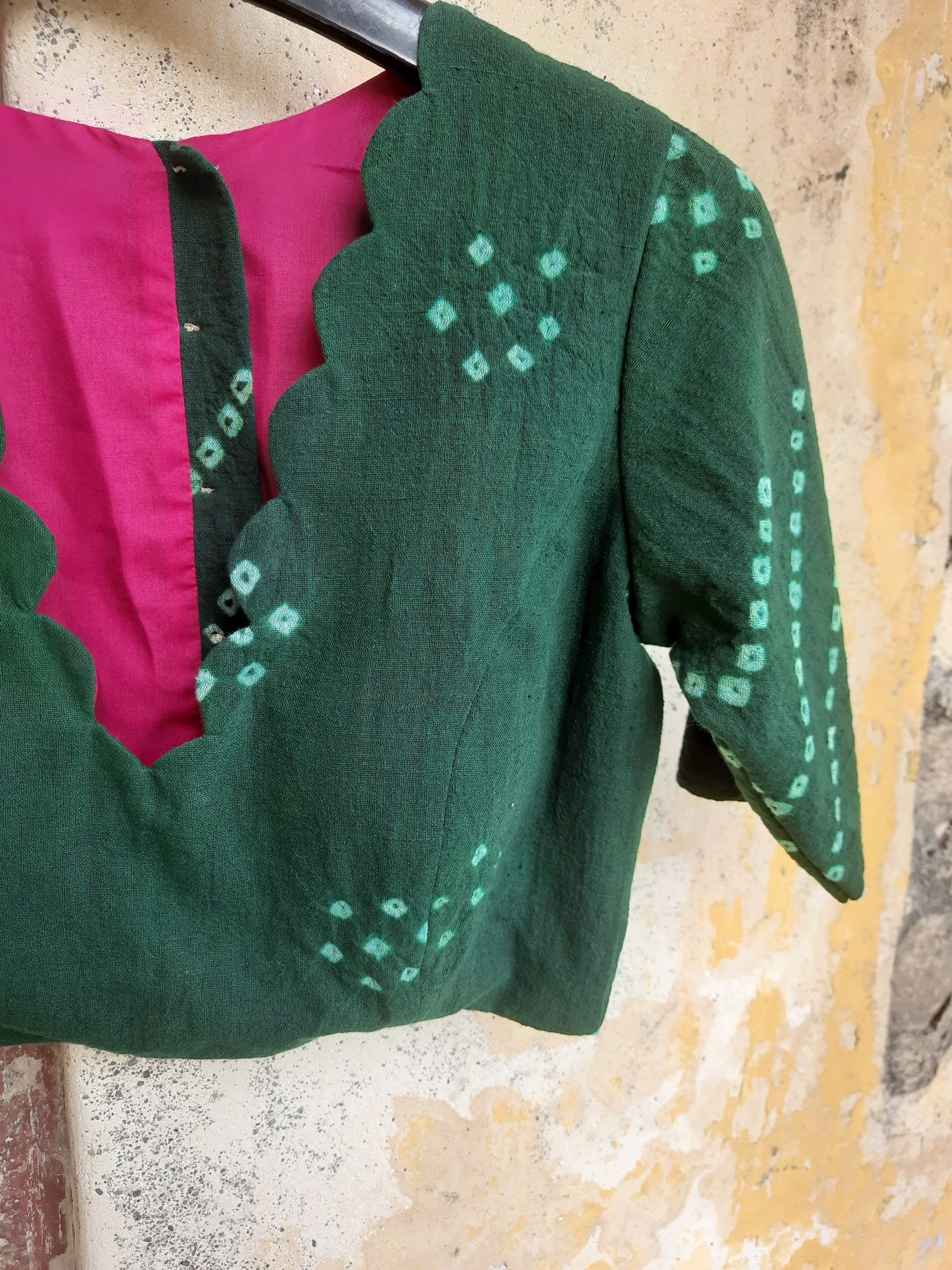 Handcrafted green Bandhani tie-dye blouse made from hand-spun and handwoven organic cotton, featuring a scalloped deep V-neck, pink lining, padded design, and back button closure - festive, elegant, and eco-conscious.