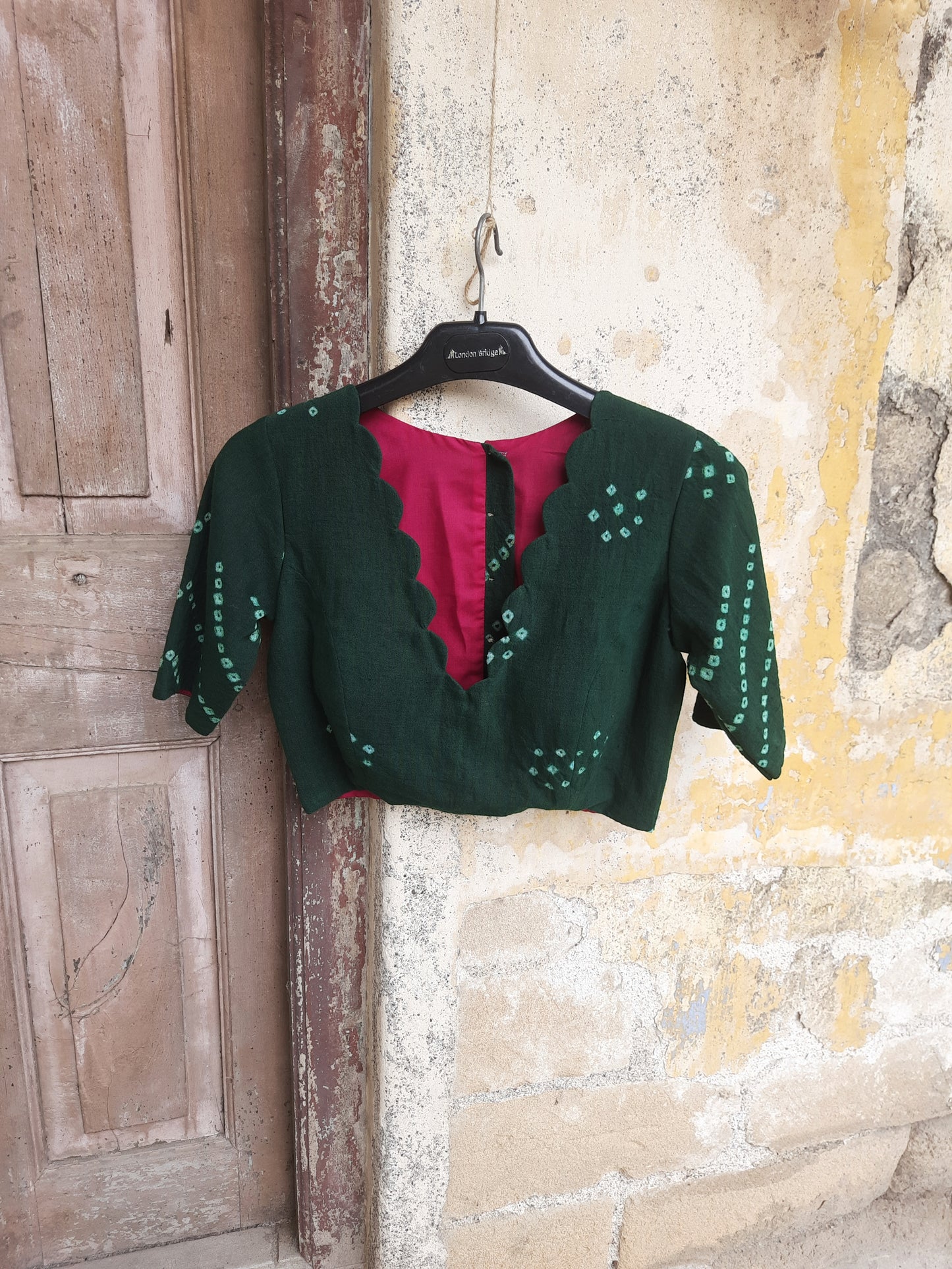 Handcrafted green Bandhani tie-dye blouse made from hand-spun and handwoven organic cotton, featuring a scalloped deep V-neck, pink lining, padded design, and back button closure - festive, elegant, and eco-conscious.