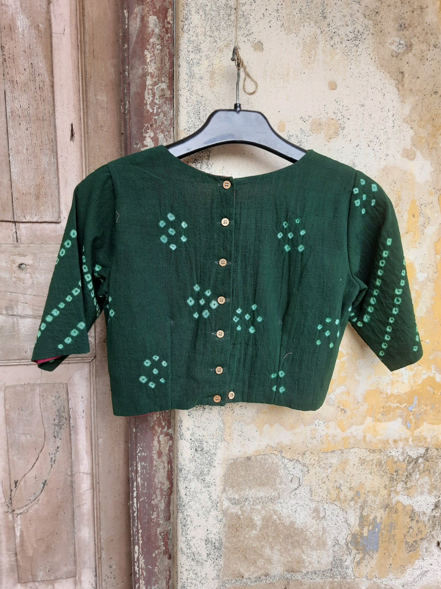 Handcrafted green Bandhani tie-dye blouse made from hand-spun and handwoven organic cotton, featuring a scalloped deep V-neck, pink lining, padded design, and back button closure - festive, elegant, and eco-conscious.