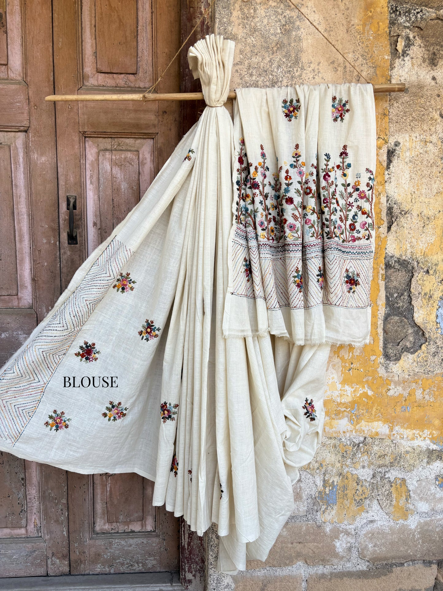 Handspun and handwoven cotton saree in natural ivory shade, featuring intricate hand embroidered floral motifs with subtle sequins. Slow made artisanal saree inspired by Basant, paired with a hand embroidered blouse piece.