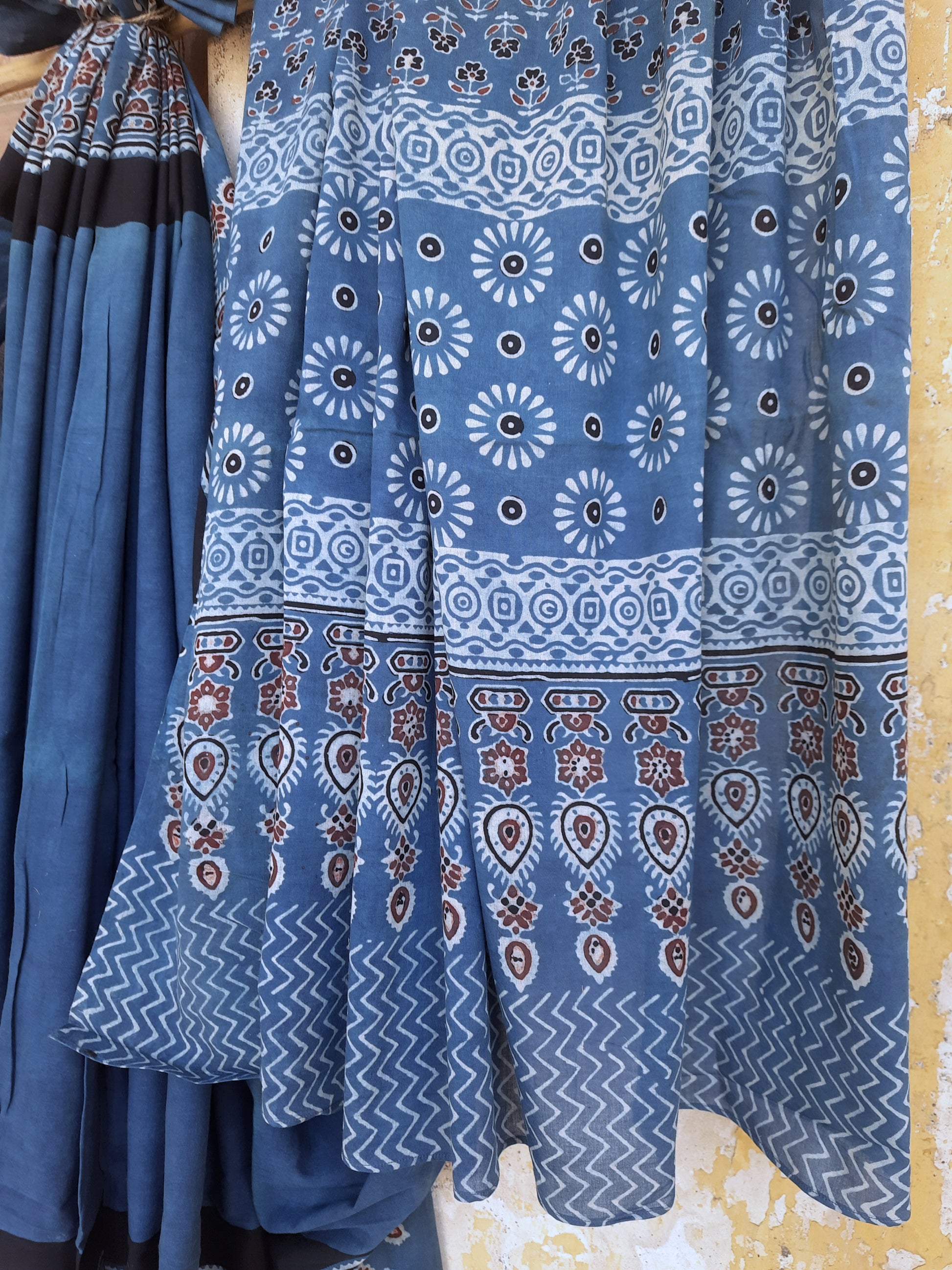 Solid indigo dyed Ajrakh hand block printed cotton saree featuring a calm indigo body with intricately printed Ajrakh borders and pallu. Natural dyed, breathable and slow made saree handcrafted by artisans in Gujarat.