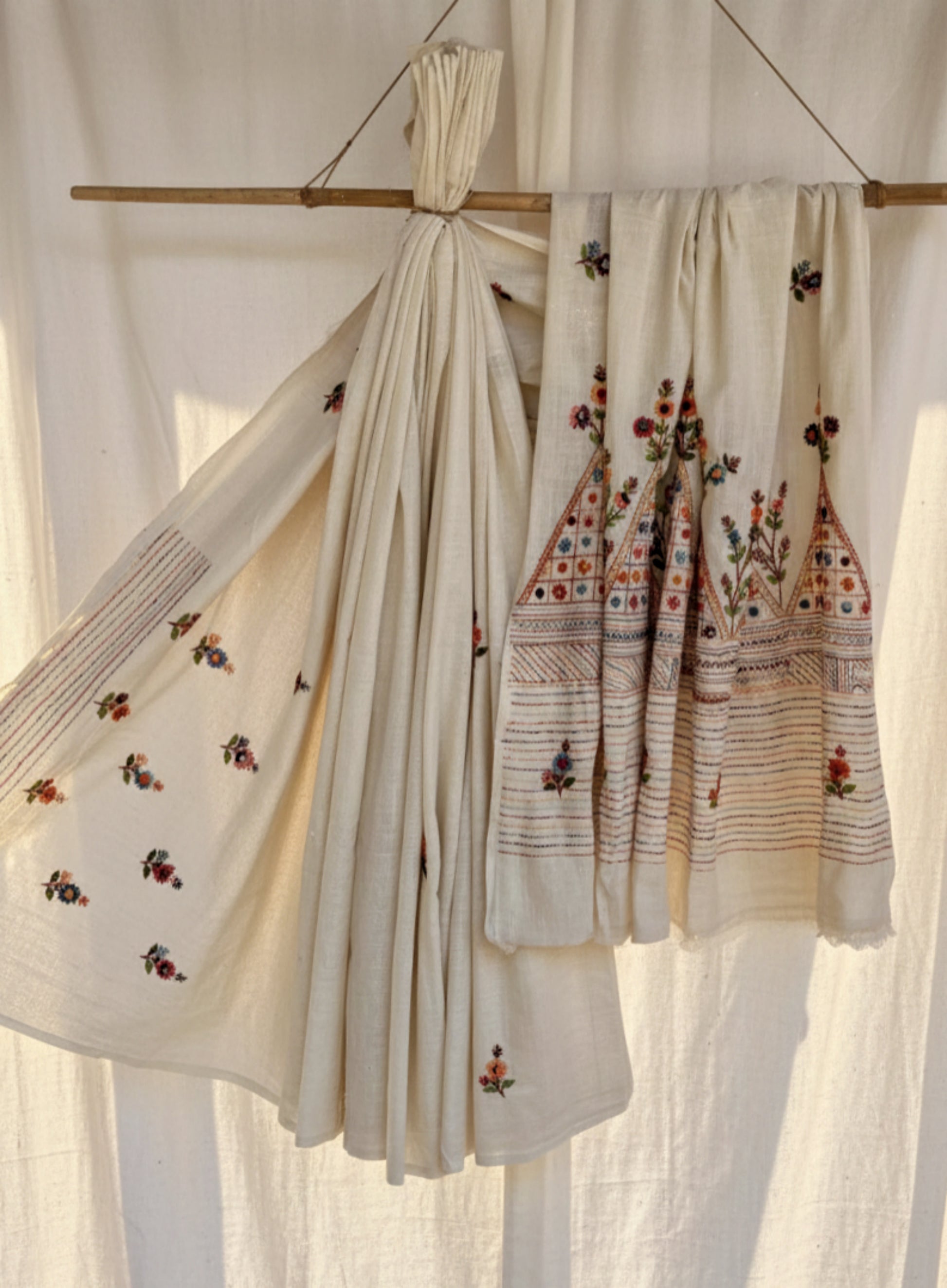 Handspun and handwoven cotton saree in warm ivory shade, featuring delicate hand embroidered floral and linear motifs with subtle sequin detailing. Slow made artisanal saree named Kusum, paired with a hand embroidered blouse piece.