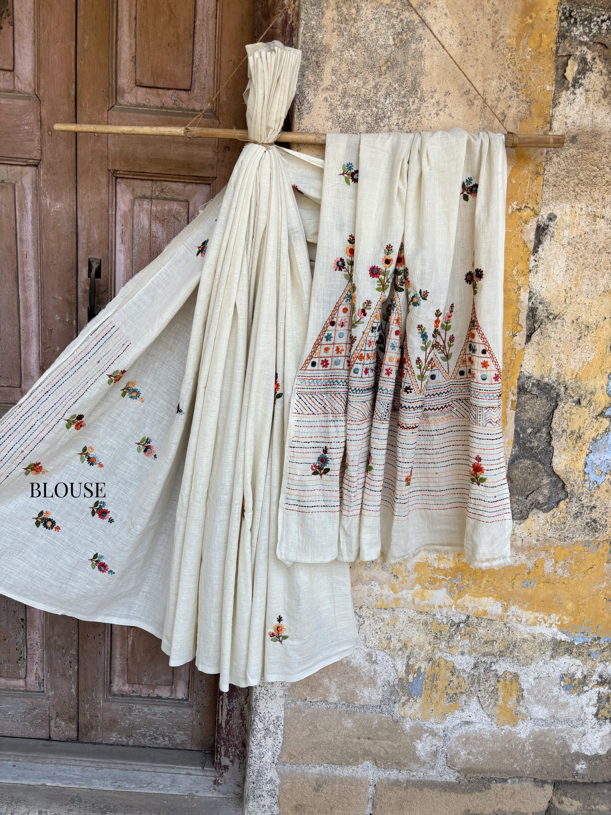 Handspun and handwoven cotton saree in warm ivory shade, featuring delicate hand embroidered floral and linear motifs with subtle sequin detailing. Slow made artisanal saree named Kusum, paired with a hand embroidered blouse piece.