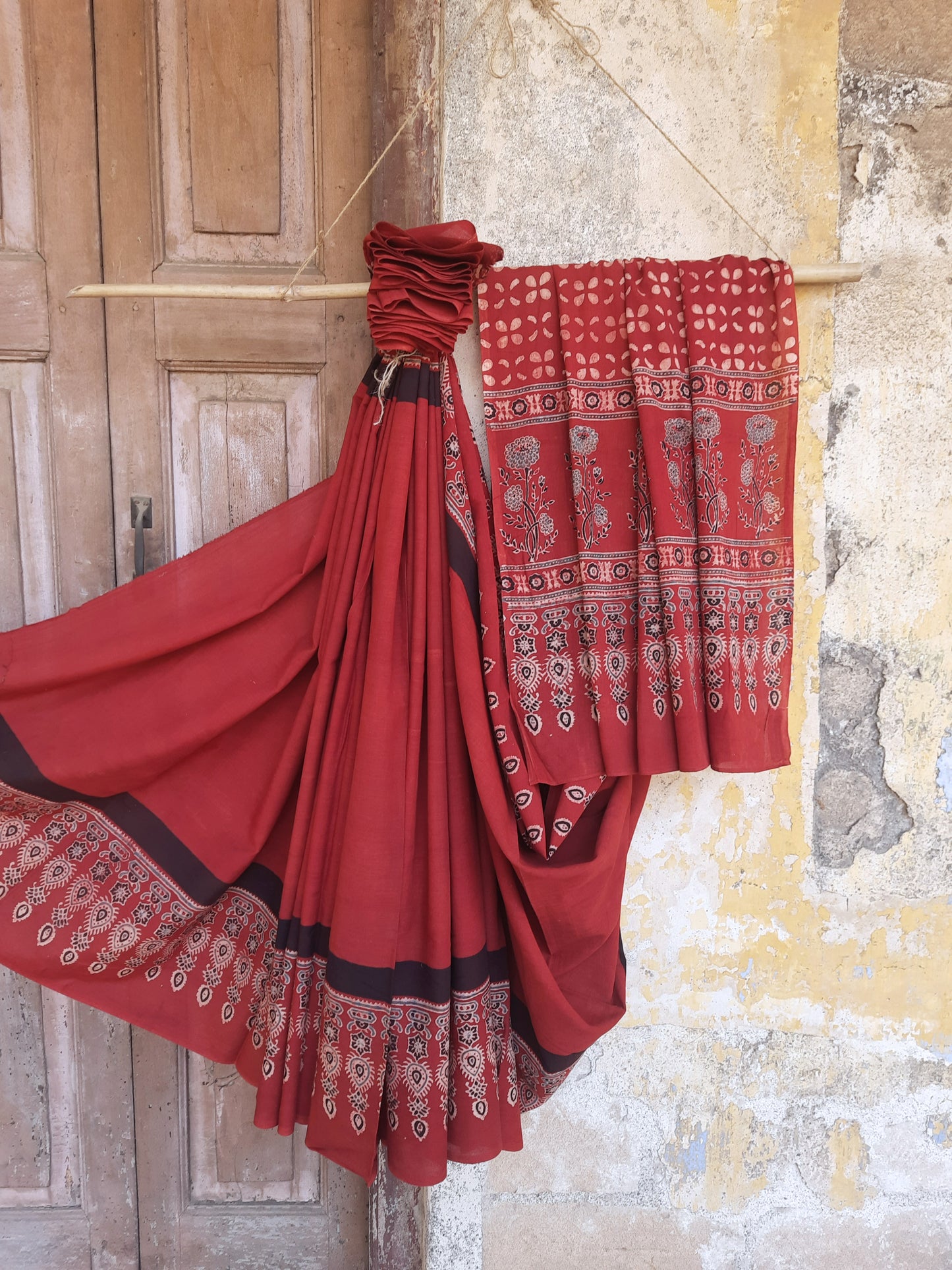 Madder red cotton Ajrakh hand block print saree featuring a solid dyed body, intricately printed Ajrakh borders, and a richly patterned pallu, naturally dyed using madder with a running blouse piece, handcrafted in India.