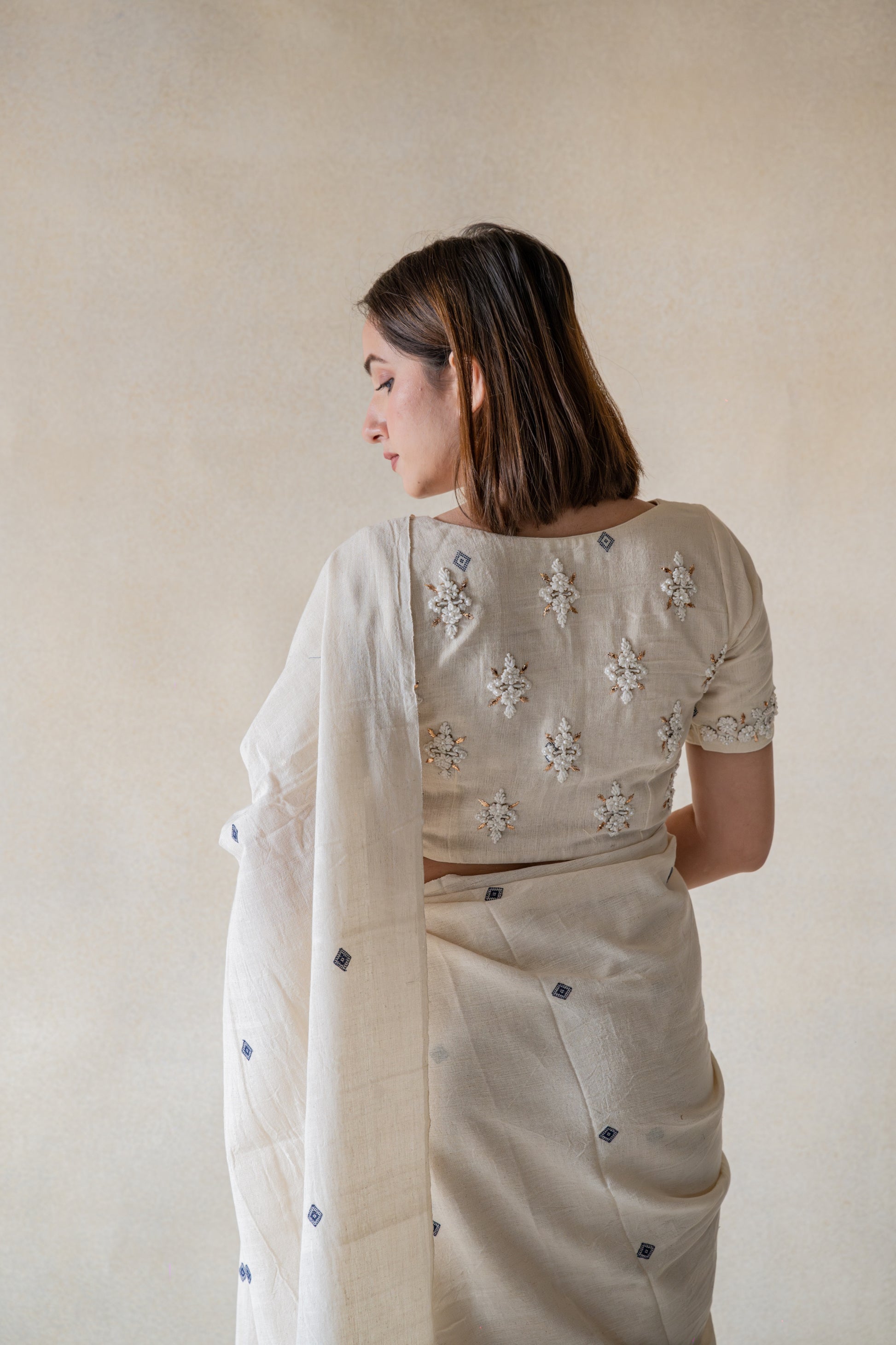 Off-white hand-embroidered organic cotton blouse, handspun and handwoven, featuring detailed embroidery on back and sleeves hem, closed round neck, 11-inch sleeves, handmade and slow-made artisan blouse.