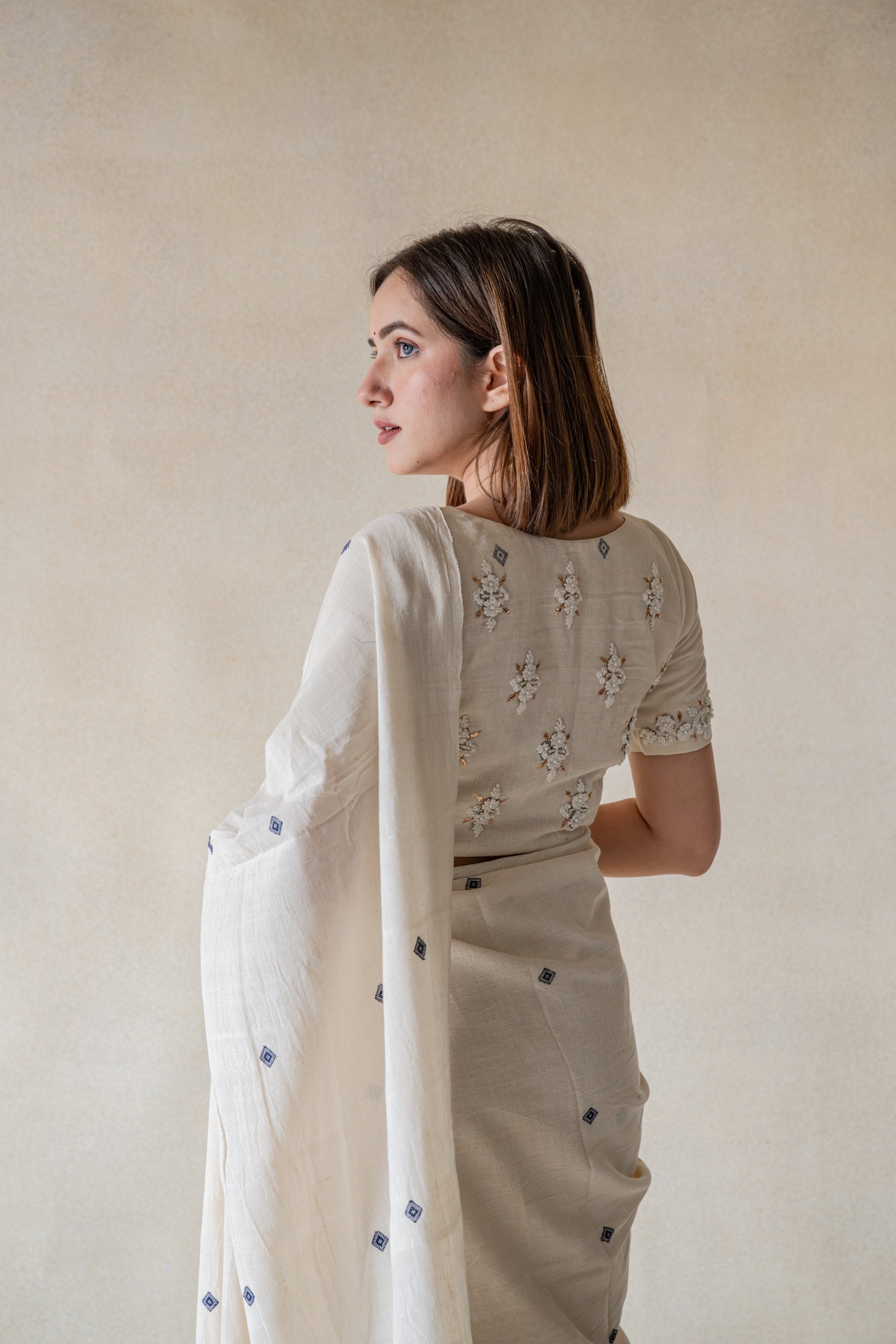 Off-white hand-embroidered organic cotton blouse, handspun and handwoven, featuring detailed embroidery on back and sleeves hem, closed round neck, 11-inch sleeves, handmade and slow-made artisan blouse.