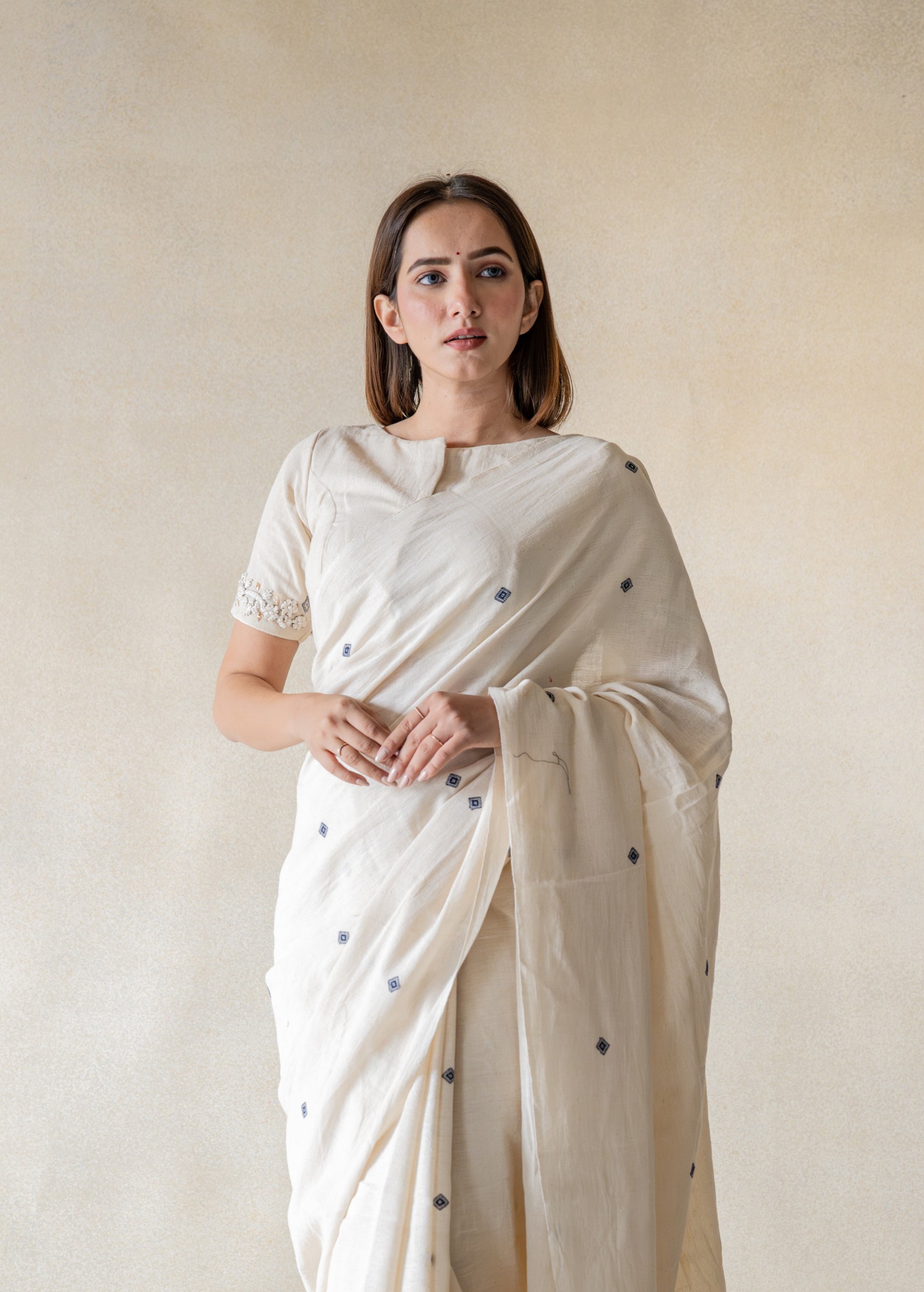 Off-white hand-embroidered organic cotton blouse, handspun and handwoven, featuring detailed embroidery on back and sleeves hem, closed round neck, 11-inch sleeves, handmade and slow-made artisan blouse.