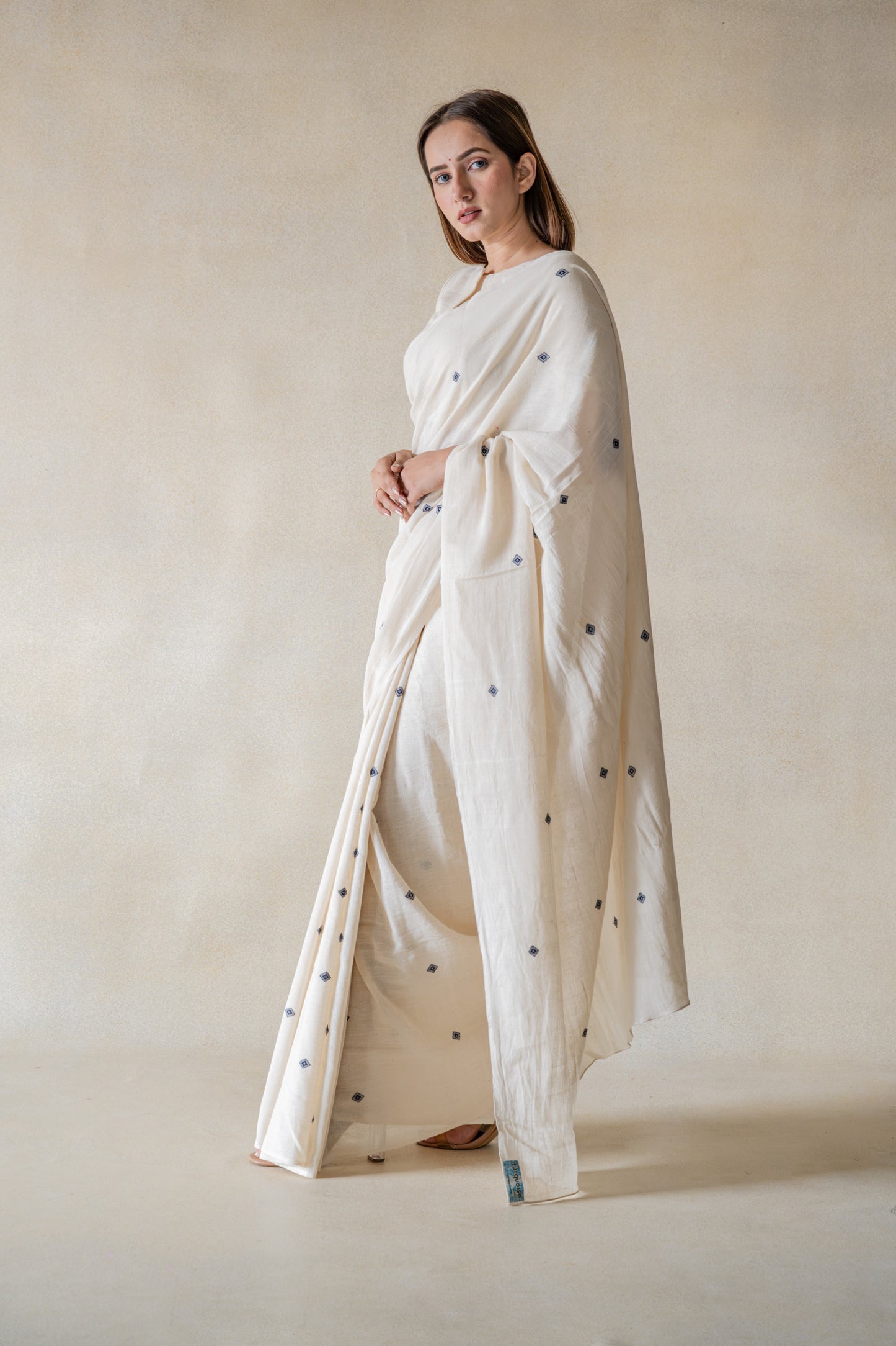 Off-white handspun and handwoven organic cotton saree crafted by artisans in Gujarat, slow-made Indian wear, minimal embroidered motifs, authentic handmade saree draped on model.