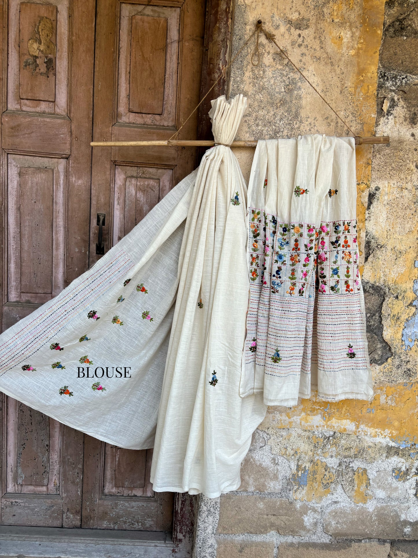 Handspun and handwoven cotton saree in warm ivory shade with expressive hand embroidered floral motifs and subtle sequin detailing. Slow made artisanal saree named Phagun, inspired by spring, with a hand embroidered blouse piece.