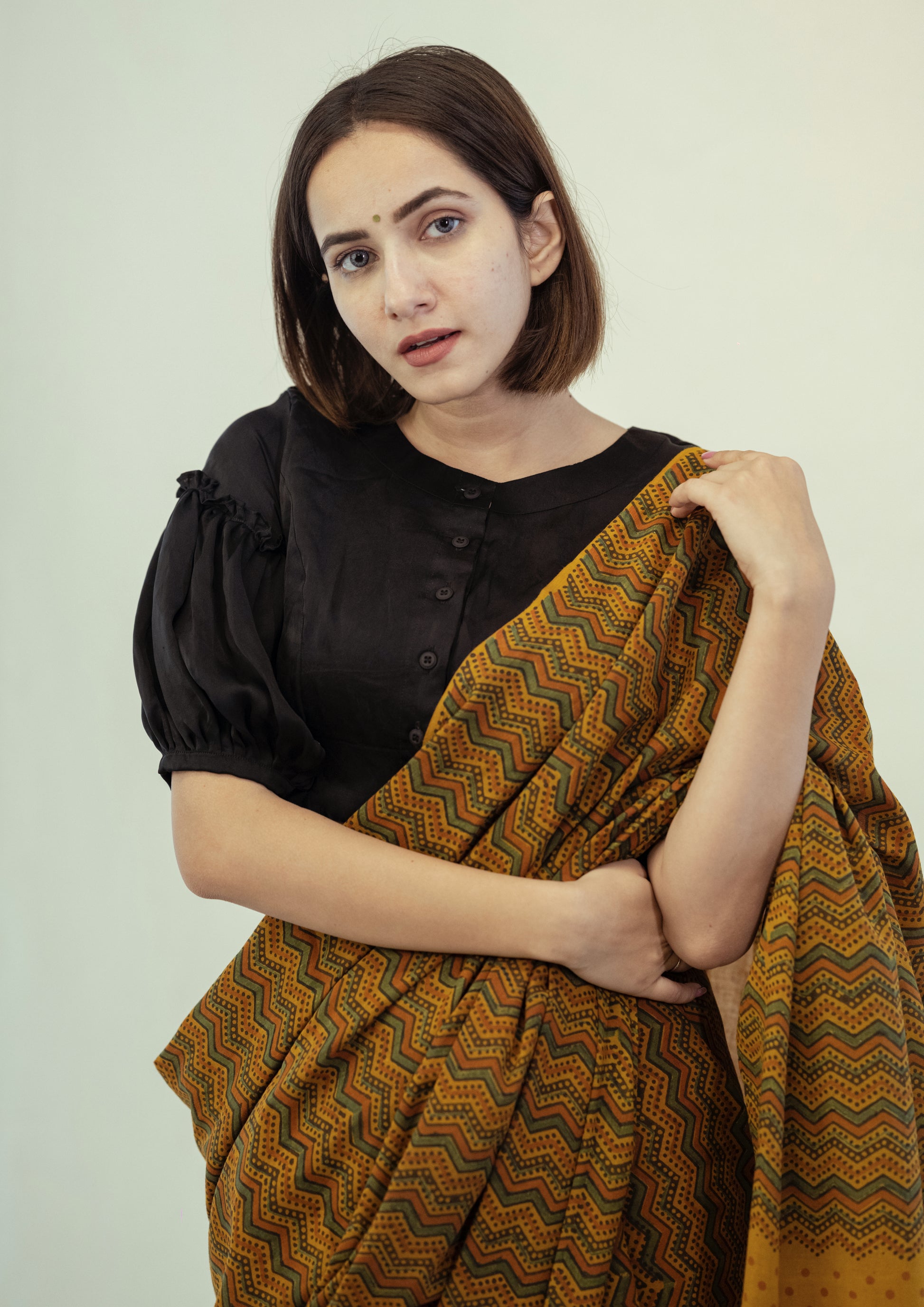 Turmeric dyed Ajrakh hand block printed cotton saree in muted mustard tone with geometric patterns.