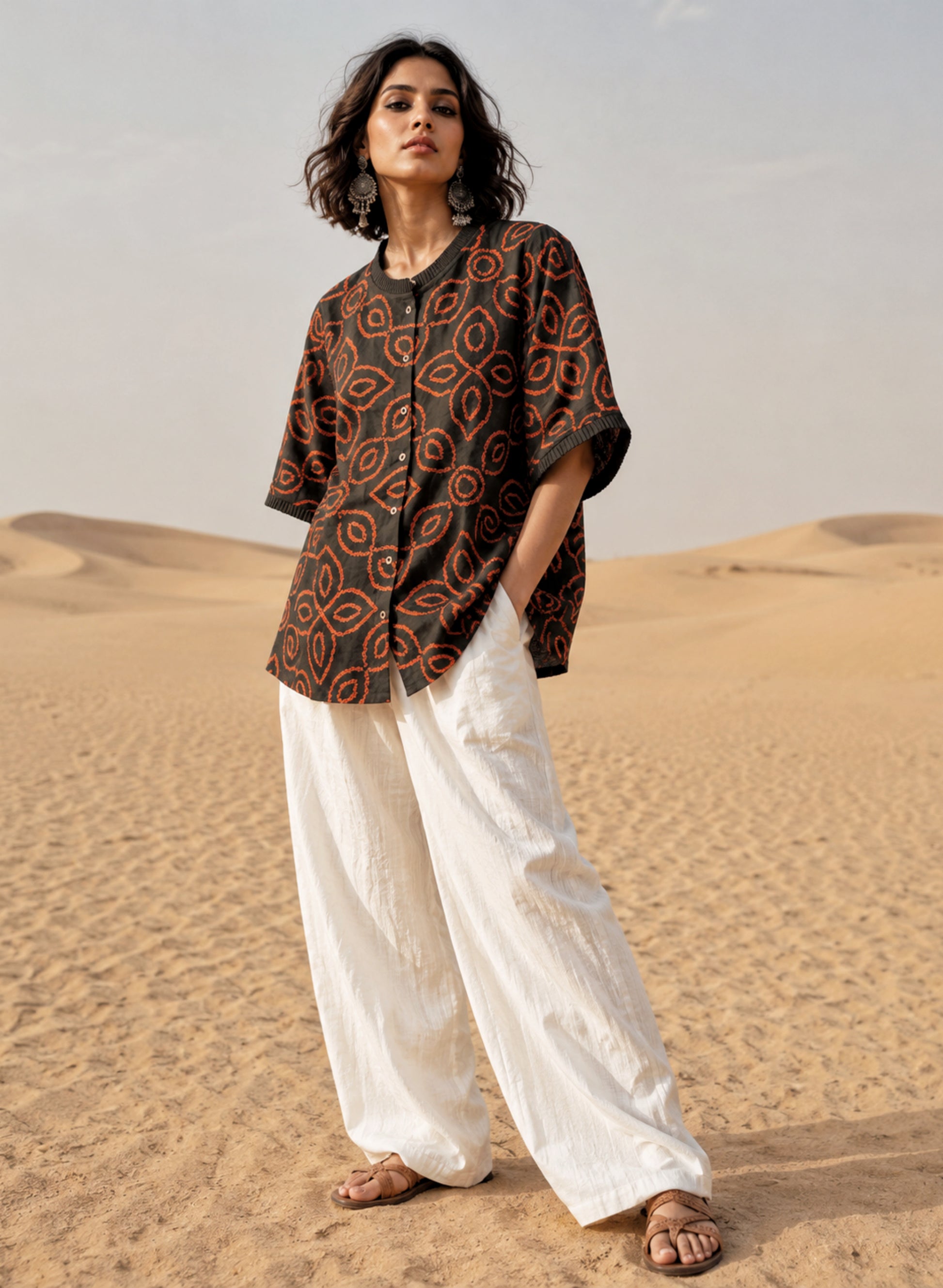 Jhankar Bandhani cotton shirt in smoky charcoal grey with burnt rust orange floral motifs, pleated neckline, pleated sleeve hems, coconut shell buttons, and relaxed fit.