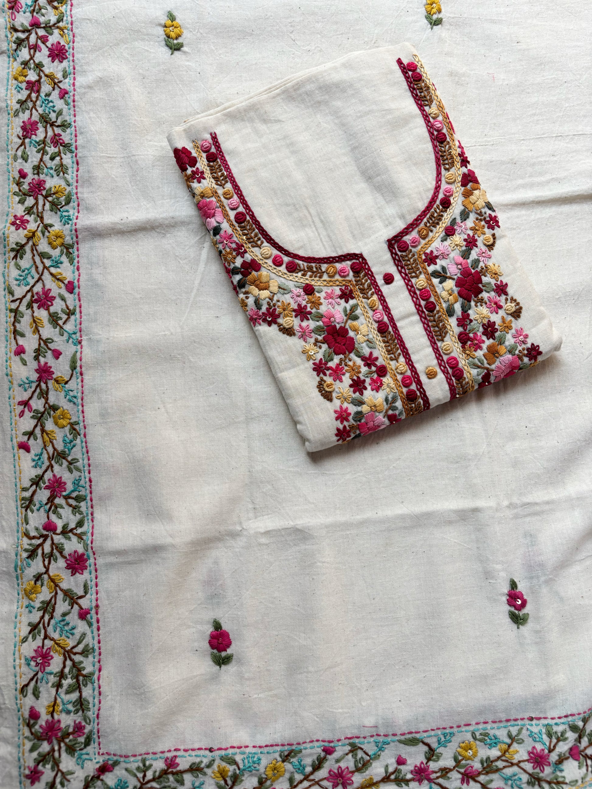Handspun cotton unstitched kurta dupatta set featuring a floral hand embroidered yoke in pink and earthy tones, small butti motifs on the kurta, and a matching hand embroidered dupatta with tassels.