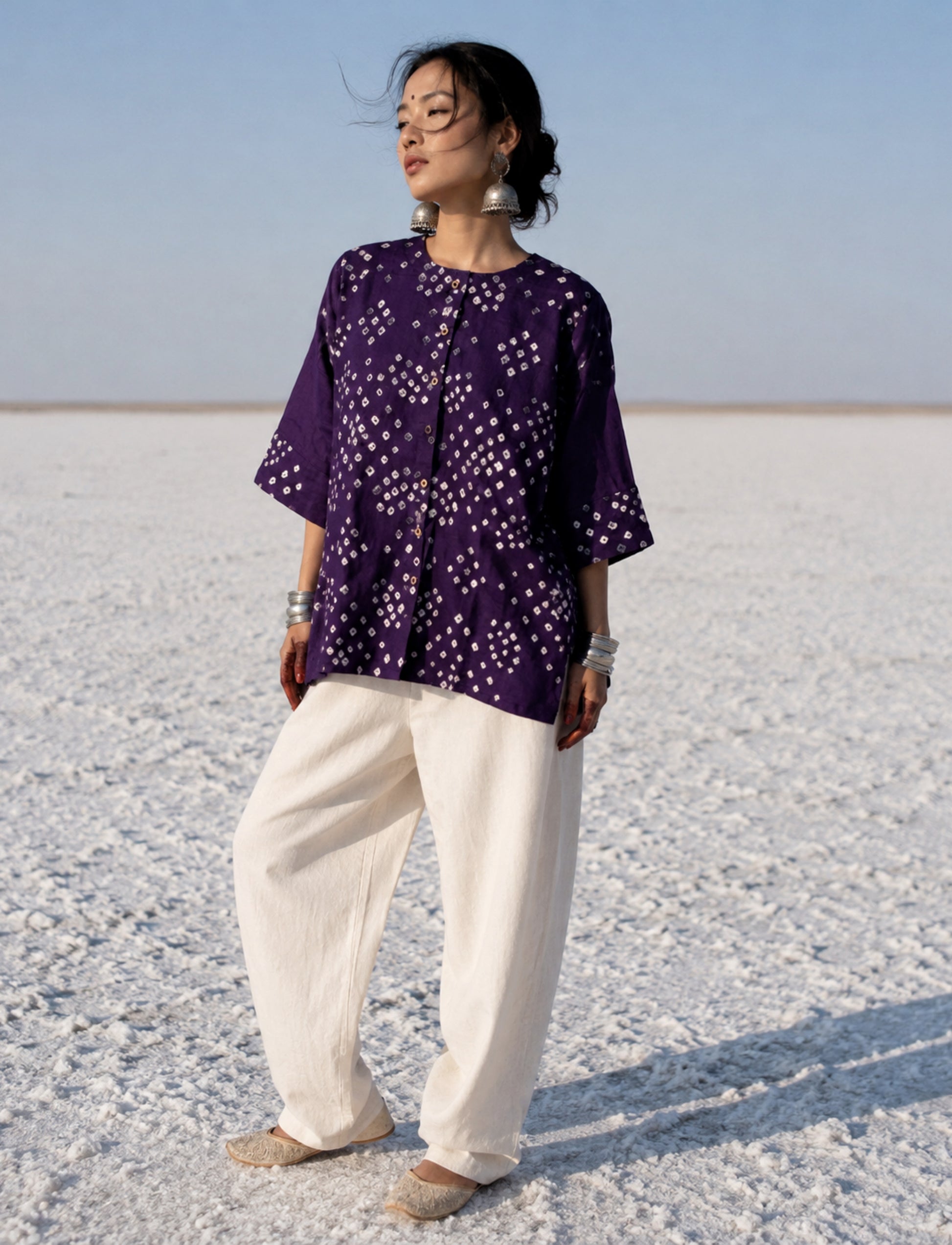 Handcrafted Deep Aubergine Cotton Satin Bandhani Shirt featuring hand tie-dyed geometric Bandhani motifs, a round neckline, wooden button closure, elbow-length sleeves with Bandhani cuffs, relaxed fit, and short side slits.