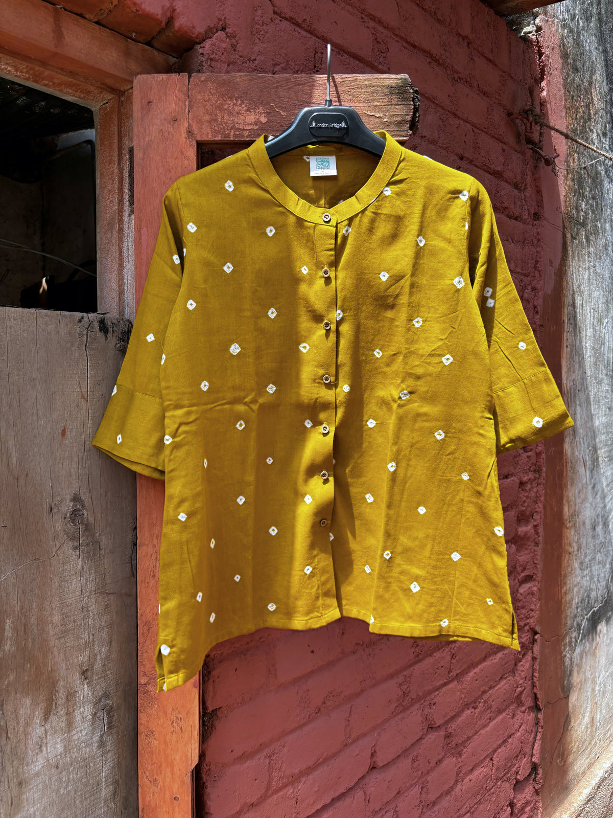 Front view of Tesu mustard-ochre cotton satin shirt with ivory Bandhani motifs, soft mandarin collar and front buttons