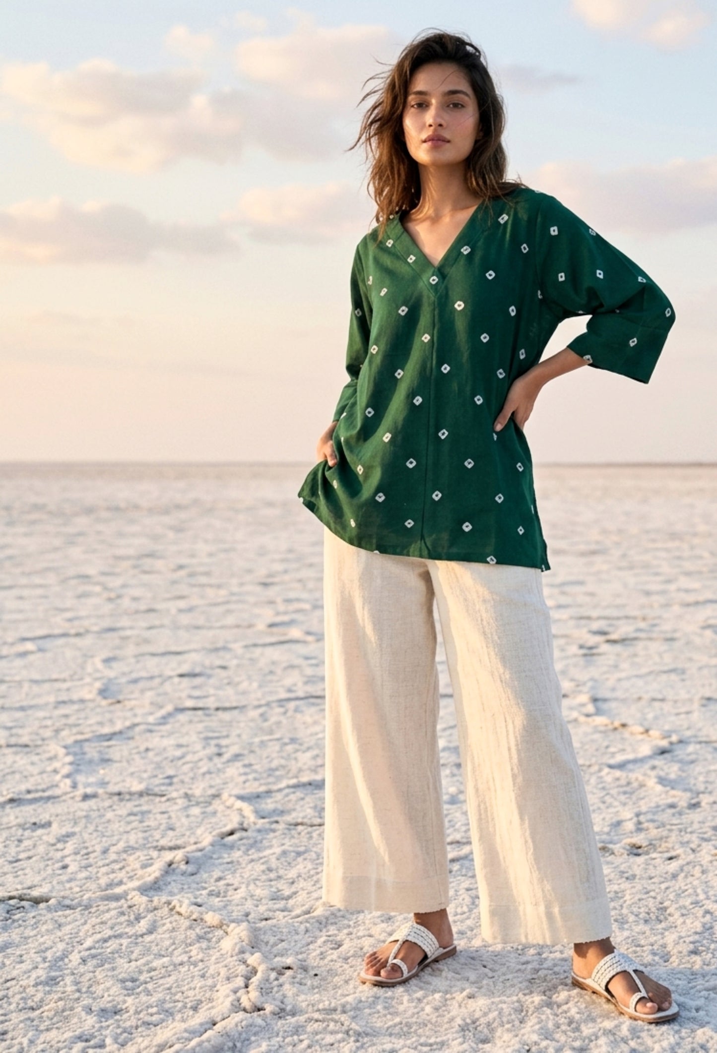 Emerald green cotton satin Bandhani top with hand tie-dyed white motifs, V-neckline, elbow-length sleeves, relaxed fit, and scattered Bandhani pattern.