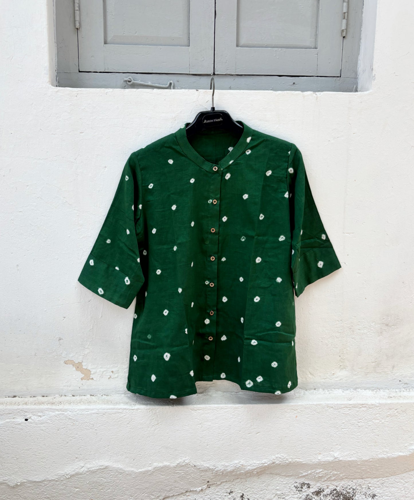 Forest green cotton satin Bandhani shirt with hand tie-dyed white motifs, soft mandarin collar, coconut shell buttons, elbow-length sleeves, and relaxed fit.