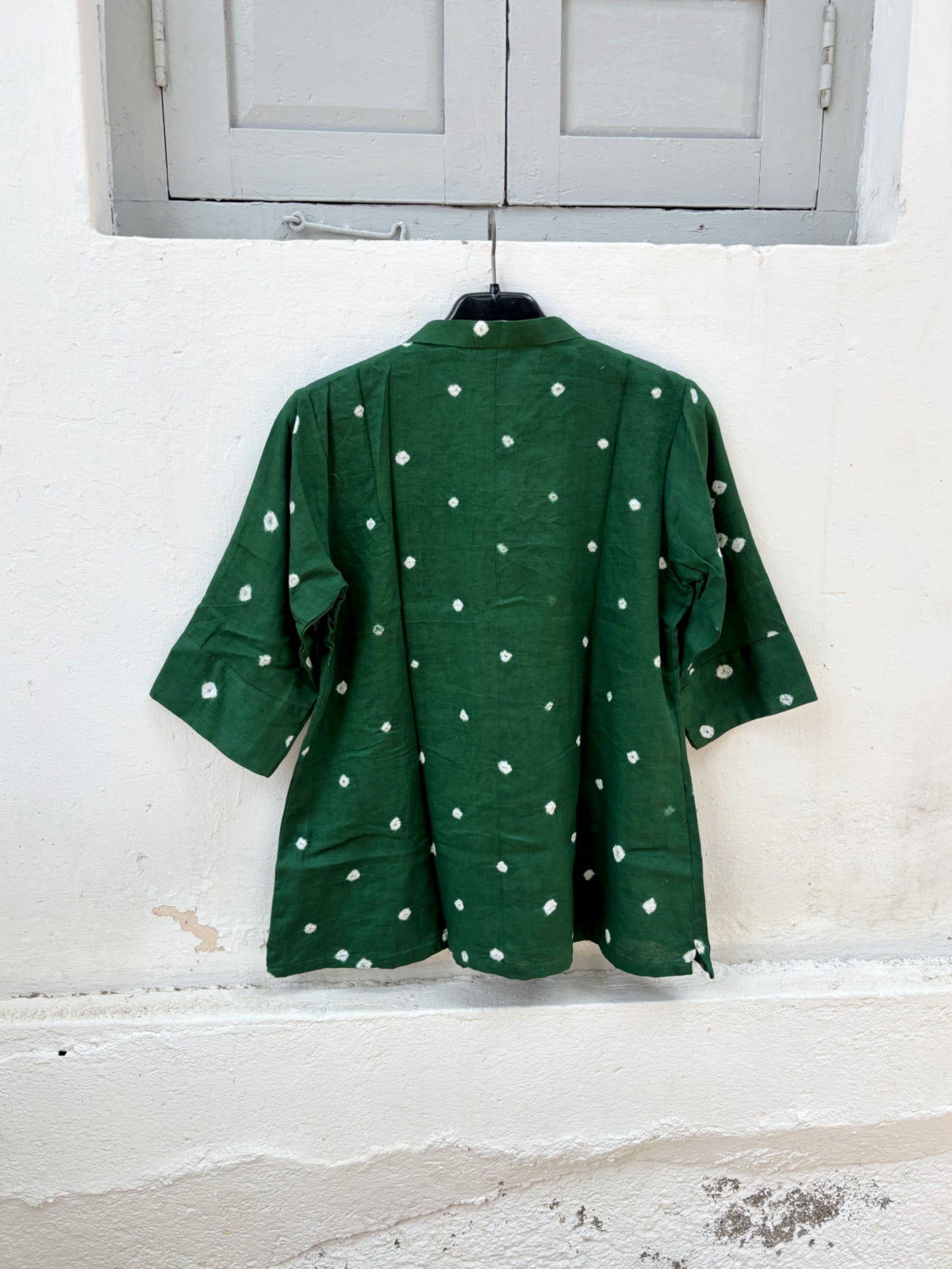 Forest green cotton satin Bandhani shirt with hand tie-dyed white motifs, soft mandarin collar, coconut shell buttons, elbow-length sleeves, and relaxed fit.
