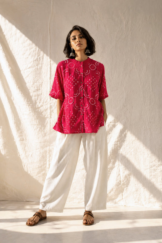 Hand tie-dyed Gulnaar Bandhani cotton satin shirt in deep bougainvillea pink with pleated neckline, pleated sleeve hems and handcrafted Bandhani motifs.